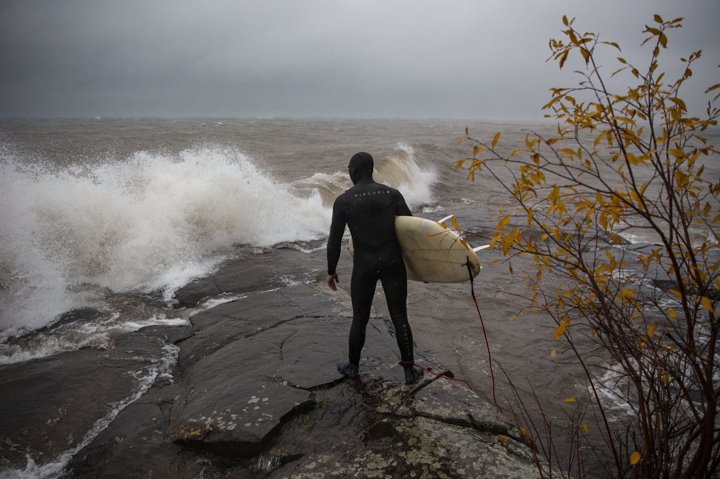 Kevin Milligan surveyed the waves and coastline before surfing on Monday. He was one of the first people out riding the massive waves of Lake Superior on Monday.