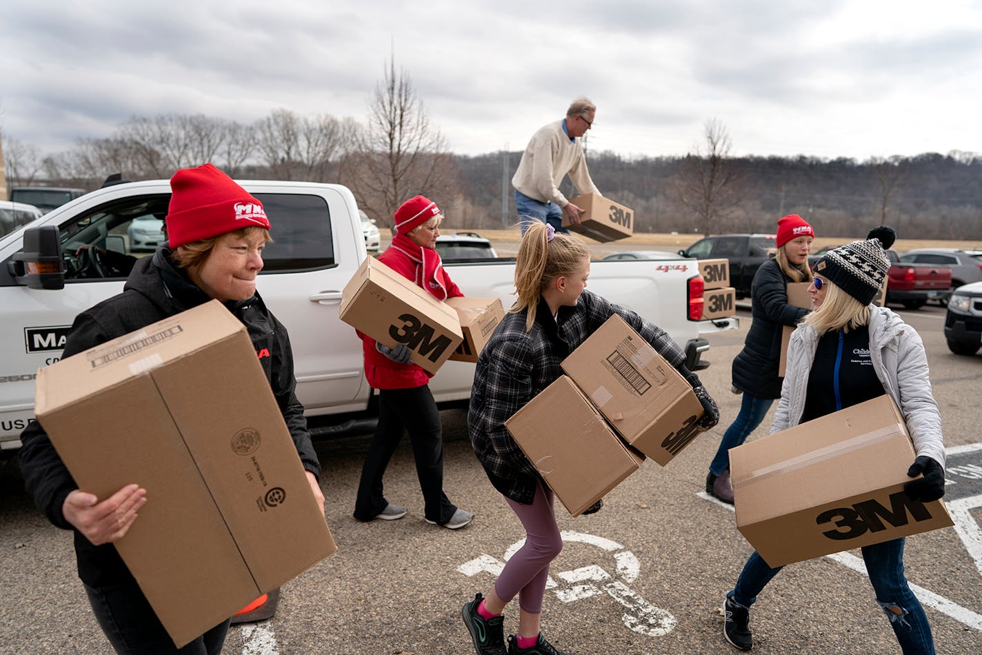 Kim Lutes, left, a registered nurse and others carried 1,200 N95 masks donated by Rich Forstner, president at Mavo Systems. The Minnesota Nurses Association held collection drives Sunday.