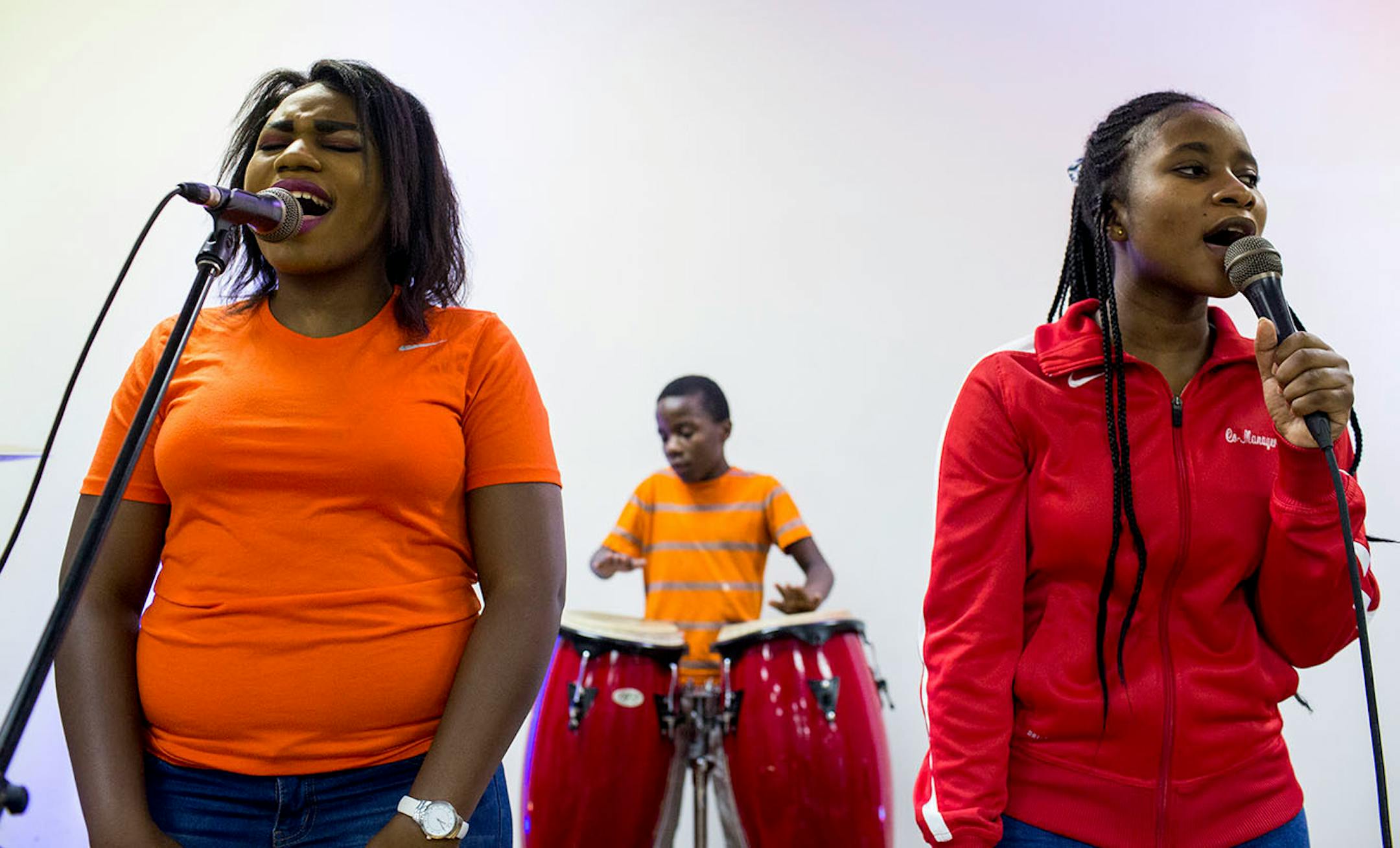Lydia, Believe and Gloria Mihigo (from left to right) perform while people enter the church service for African refugees, at Bethel Christian Fellowship Church.