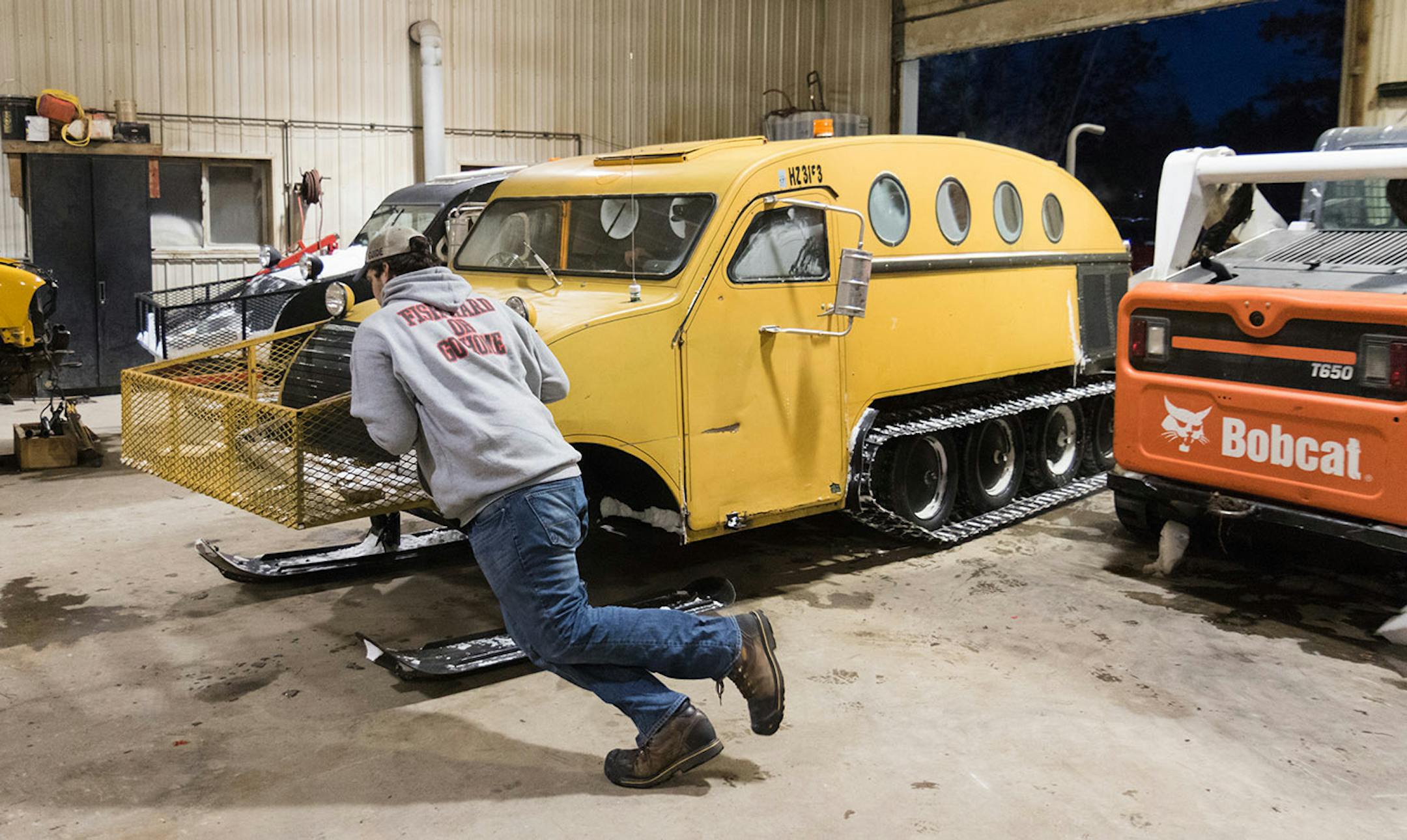 Mike Marquardt pushes on the front of Joe Anderson's bombardier to turn it as Anderson pulls into the garage where Sportsman's keeps the vehicles. The skis make turning on hard surfaces such as concrete almost impossible without assistance.