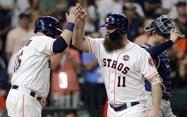 Houston Astros' Brian McCann (16) and Evan Gattis (11) celebrate at the plate, next to Minnesota Twins catcher Mitch Garver (23), after they scored on
