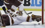 Minnesota goalie Eric Schierhorn reaches to stop the puck during the first period of an NCAA college hockey semifinal match against Penn State in the 