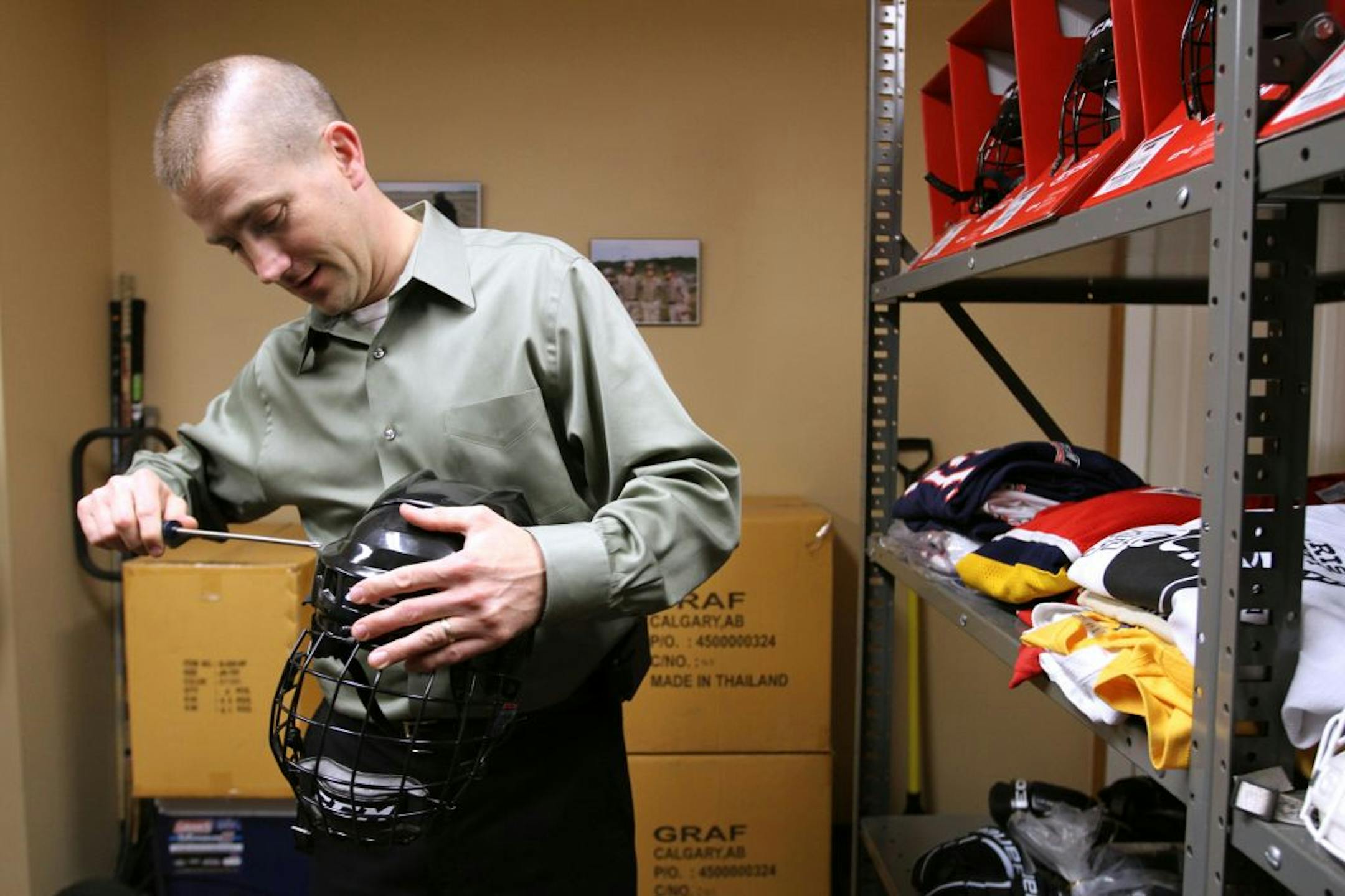Shane Hudella, co-founder of Defending the Blue Line in Hastings, adjusted a hockey helmet for 3-year-old Elias Tomaska.