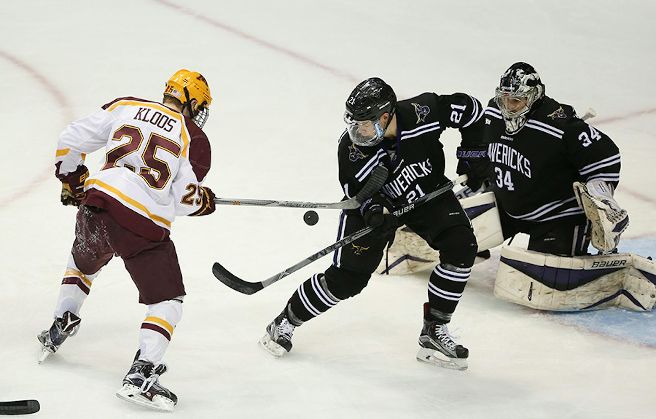 Gophers forward Justin Kloos (25) tried to slap the puck while defended by the Mavericks' Alec Vanko (21) in front of goalie Cole Huggins (34) in the first period Sunday afternoon.