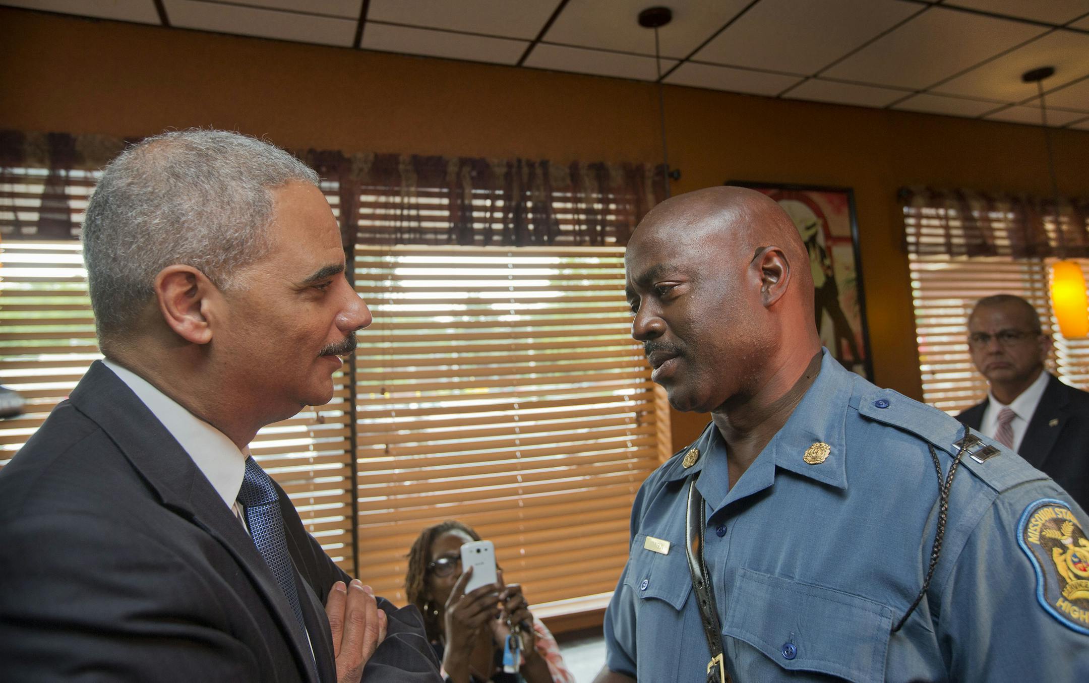 FILE - In this Aug. 20, 2014 file-pool photo, Attorney General Eric Holder speaks with Capt. Ron Johnson of the Missouri State Highway Patrol at Drake's Place Restaurant in Ferguson, Mo. As local authorities in Missouri near the end of their investigation into the Ferguson shooting, a separate, ongoing federal civil rights review of the entire police department holds the greater potential to refashion the agency and spur long-lasting change, experts say. The Justice Department, which is investig