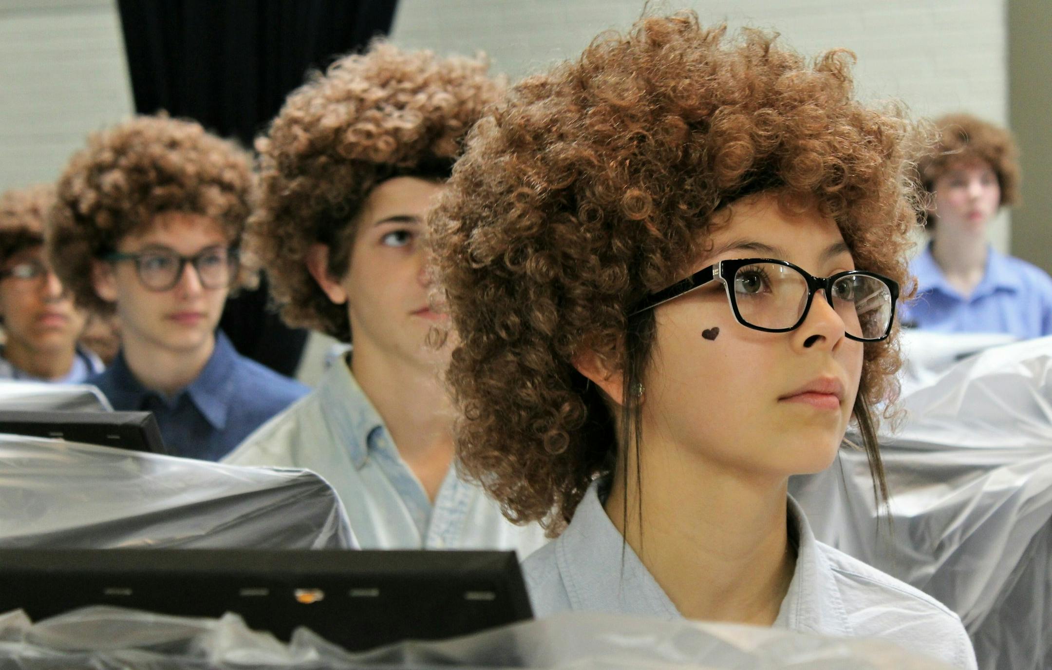 Madison Middle School art student Ariceli Martinez, wearing her Bob Ross wig, listens to the artist speak on a video screen before painting began on Flash Bob Flash Mob Day on Feb. 7, 2019 in Abilene, Texas The students donned their curliest wigs and painted little trees onto canvases to pay homage to the late painter Bob Ross. Teacher Brady Sloane said the idea came about because she wanted to reward Advanced Placement students who had been stressed out over recent projects and grades. (Greg Ja