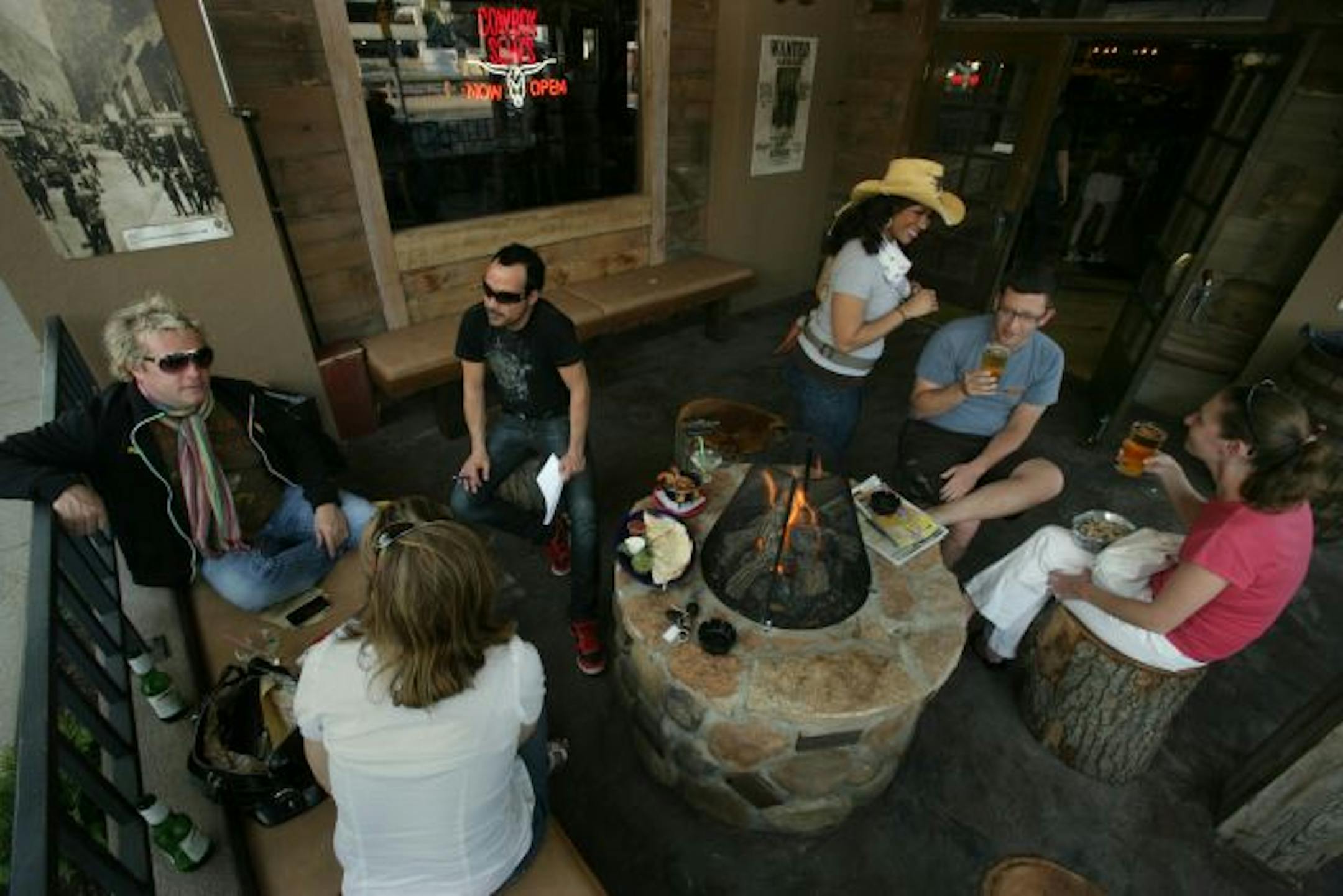 Laura Keller of Minneapolis, Jon Charles and Craig Weitz discuss business at Cowboy Slims Saloon. Waitress Leah Kain serves Mike Linzbach and Ann O'Conner a beer on the patio.