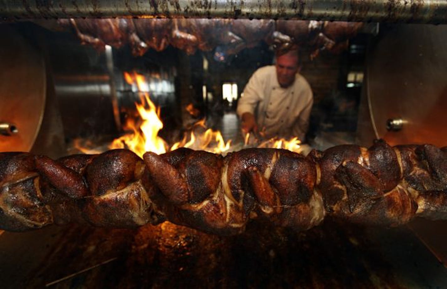 Chef James Foley adjusts the fire burning underneath the rotisserie chicken at the Porter Creek Hardwood Grill.