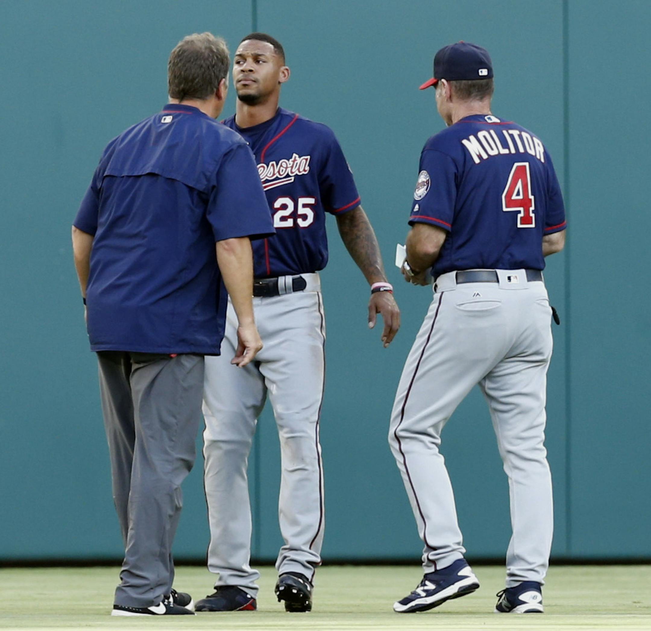Minnesota Twins center fielder Byron Buxton (25) is checked by a team trainer and manager Paul Molitor (4) after colliding into the outfield wall on a ball hit by Texas Rangers' Rougned Odor during the first inning of a baseball game Friday, July 8, 2016, in Arlington, Texas. (AP Photo/Jim Cowsert)