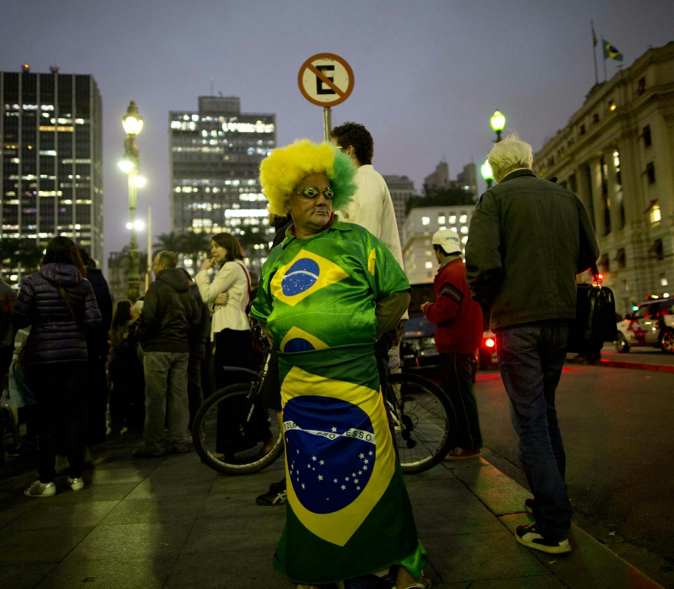 A man dressed in an outfit with Brazilian flags motifs stands on downtown corner in Sao Paulo, Brazil, Tuesday, June 10, 2014. The 2014 World Cup is set to begin Thursday, with Brazil and Croatia competing in the opening match in Sao Paulo. (AP Photo/Rodrigo Abd)