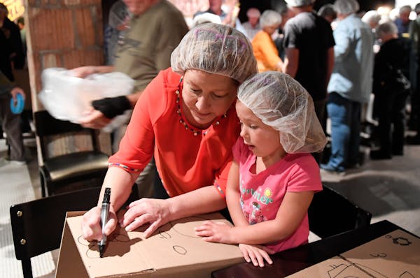 Emma Townsend, 4, of New Richmond, Wisc., drew pictures on a cardboard box that would be used to pack dried meals for Hurricane Harvey victims in Hous