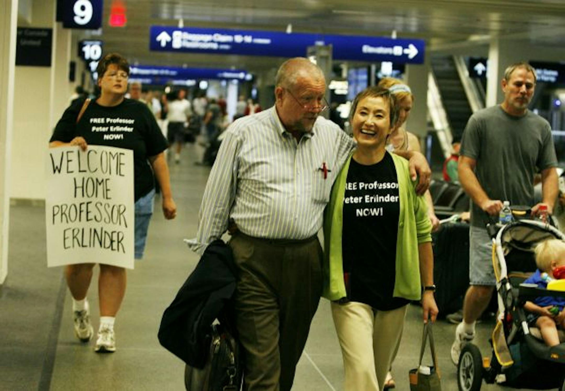 Erlinder walks towards the baggage claim with his wife Masako Usui by his side.