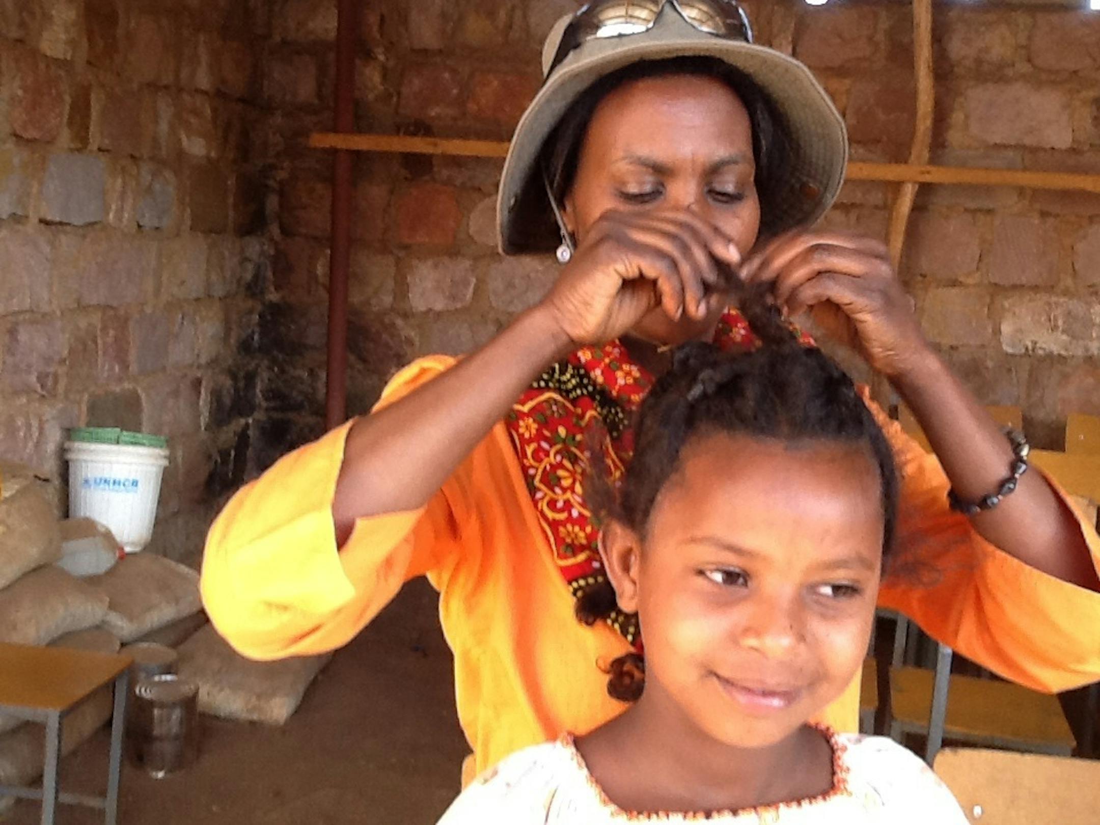 Shegitu Kebede works on a refugee girl's hair in an Ethiopian camp