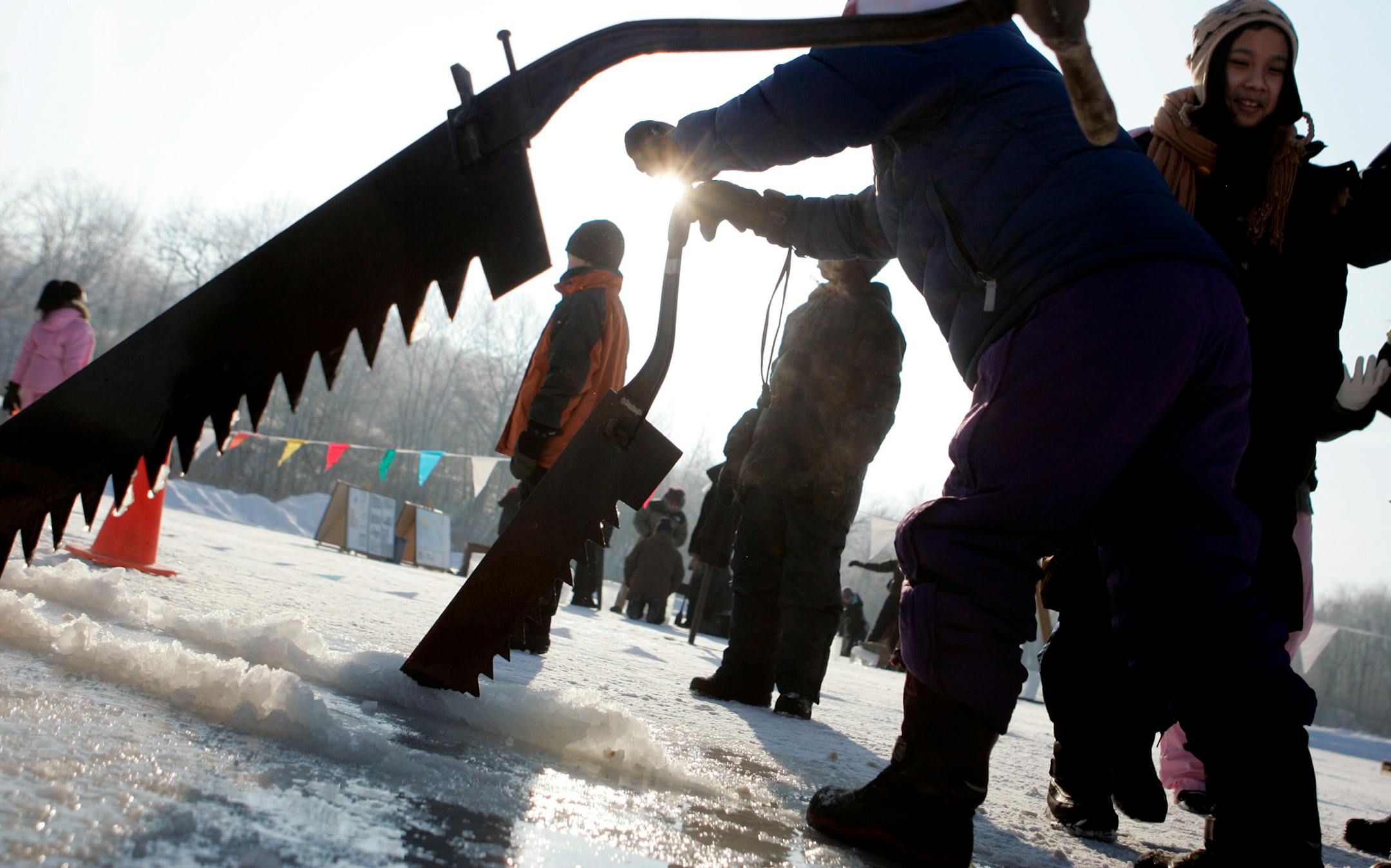 Students from Kenwood Elementary School in Minneapolis cut large blocks of ice with a handsaw during an ice harvest history day at Hyland Park Reserve in Bloomington last week. Before refrigerators, ice was harvested to keep food cold in ice boxes all summer long.