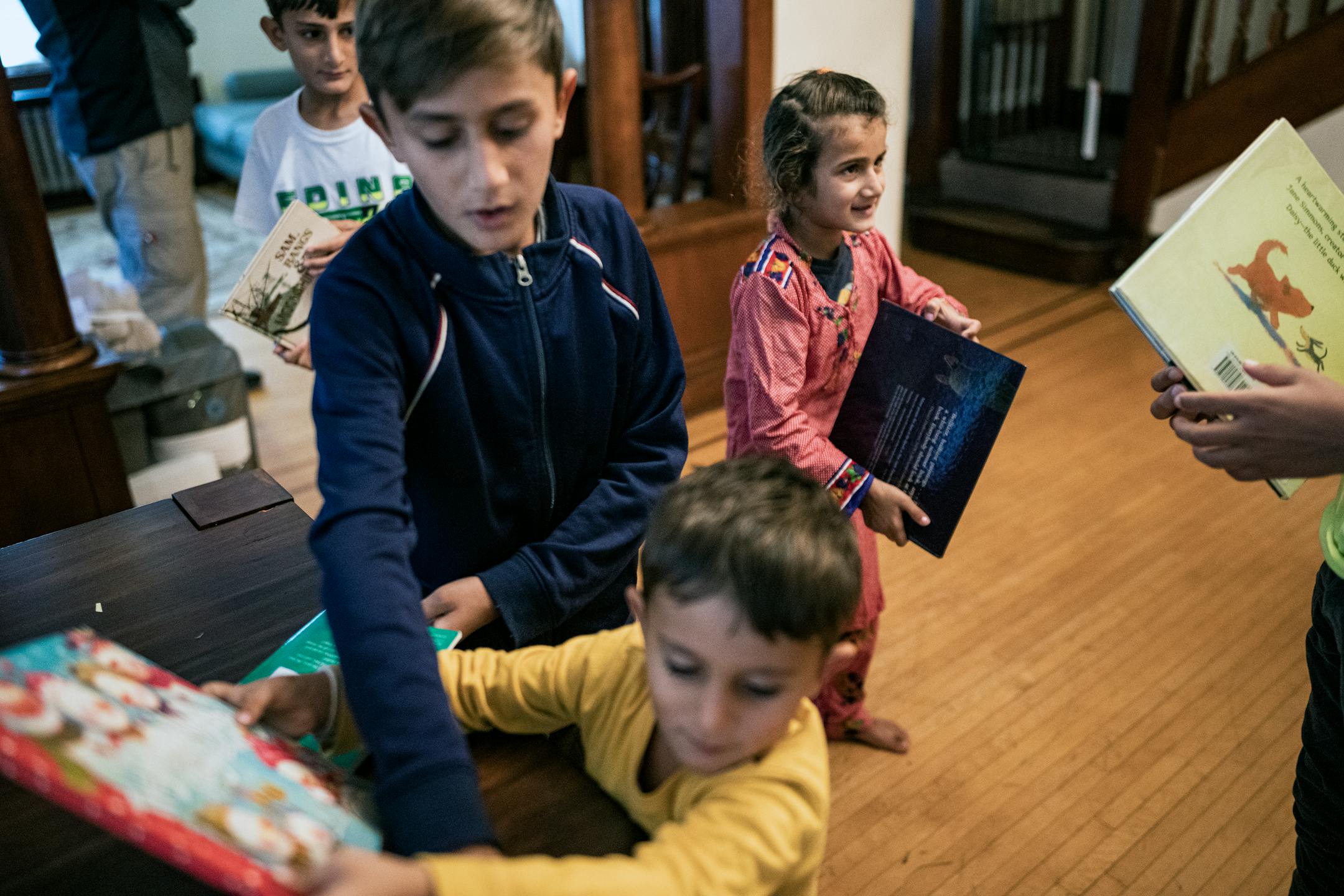 Mirwais Momand's children check out the books brought over by International Institute of Minnesota's Jane Graupman, whose non-profit is helping resettle Afghan refugees in St. Paul.