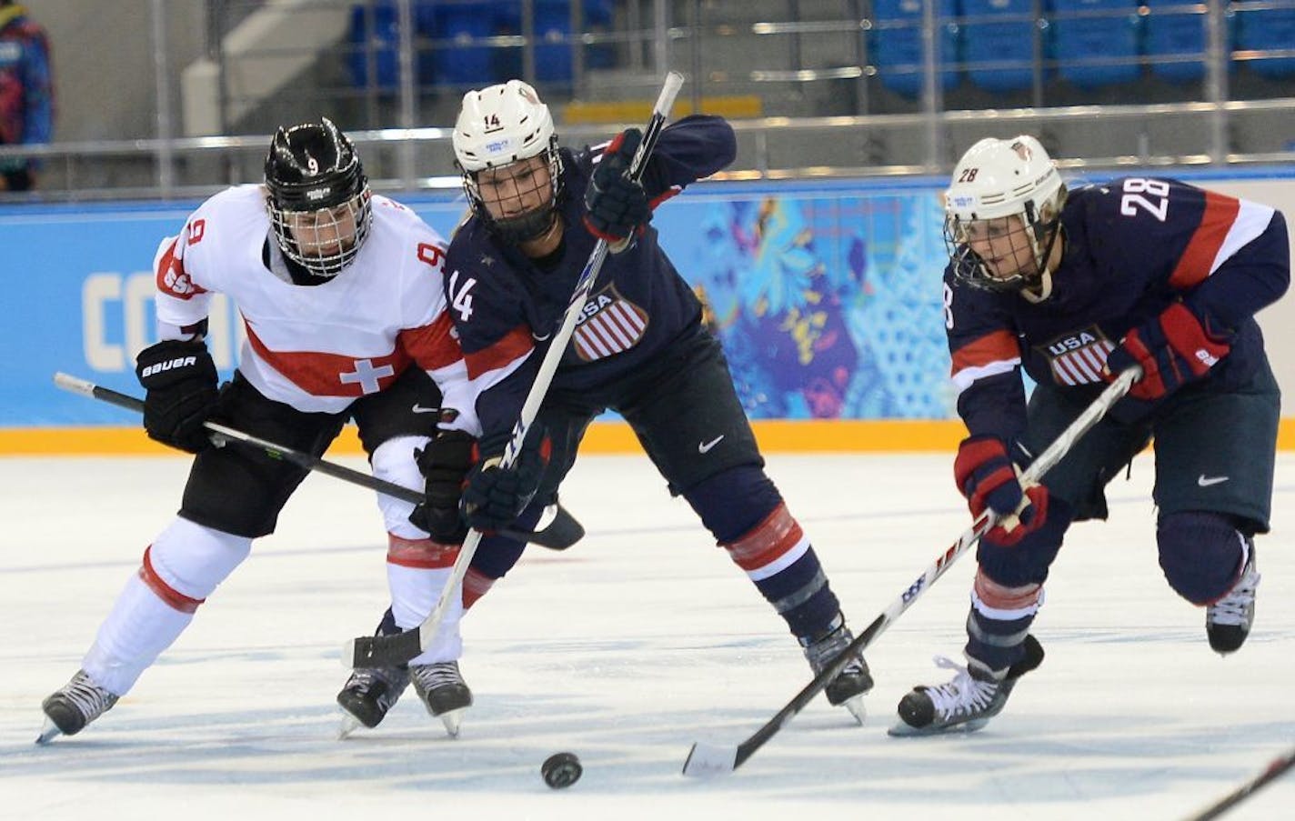 USA forward Amanda Kessel (28) gathers the puck, as USA forward Brianna Decker (14) ties up Switzerland forward Stefanie Marty (9), during the first period in a women's hockey game at the Winter Olympics in Sochi, Russia, Monday, February 10, 2014.