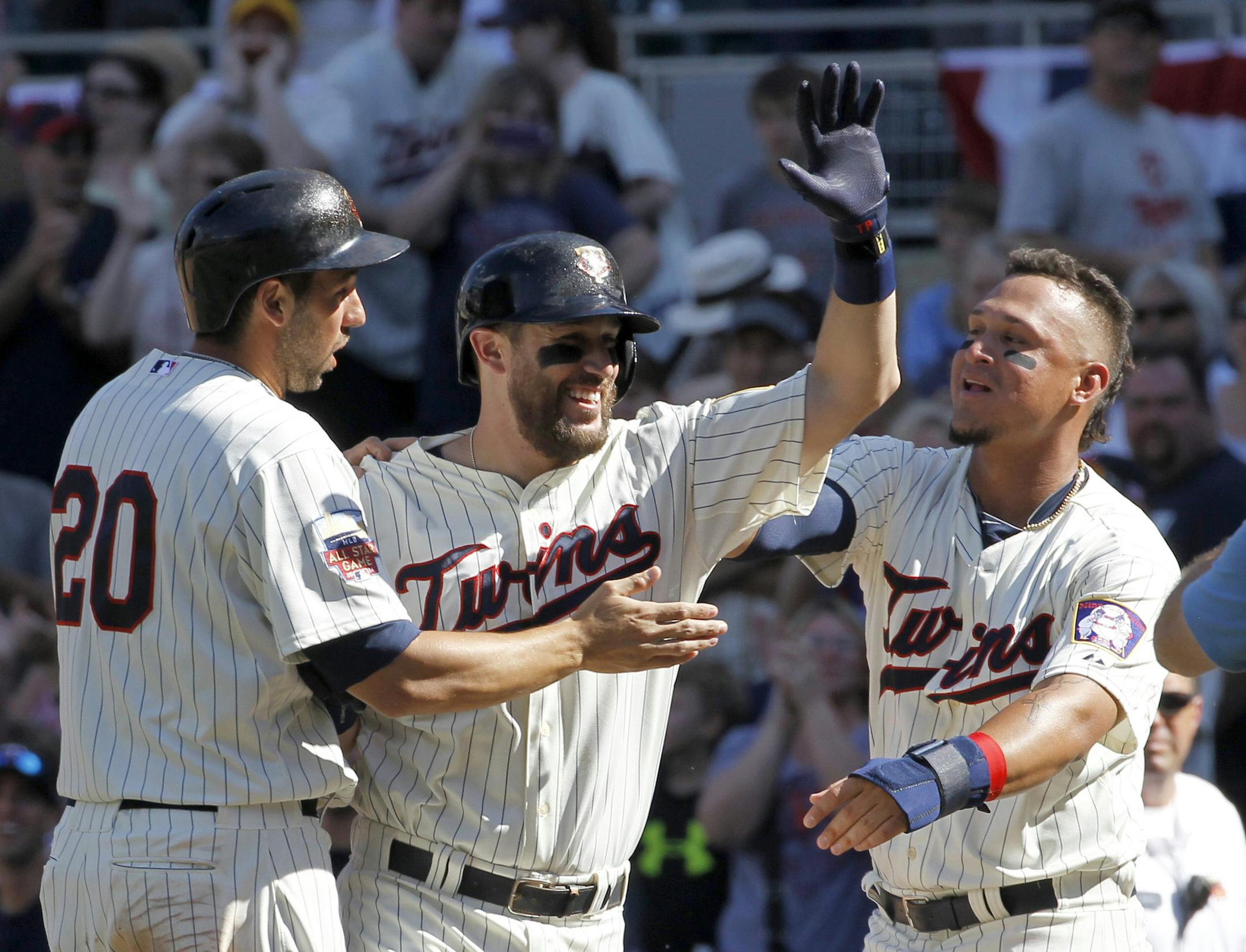 Minnesota Twins' Chris Colabello, left, and Oswaldo Arcia, right, celebrate with Trevor Plouffe, center, after Plouffe grounded into a fielder's choice and Josh Willingham scored the winning run on a throwing error by New York Yankees catcher Francisco Cervelli during the eleventh inning of a baseball game in Minneapolis, Saturday, July 5, 2014. The Twins beat the Yankees 2-1 in 11 innings. (AP Photo/Ann Heisenfelt)