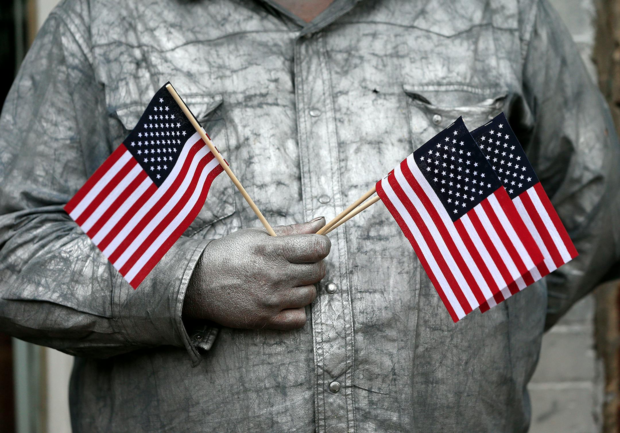 Street performer John Casey, wearing silver paint as part of his act as "The Silver Cowboy of Nashville," watches the Veterans Day parade pass by Tuesday, Nov. 11, 2014, in Nashville, Tenn. (AP Photo/Mark Humphrey)