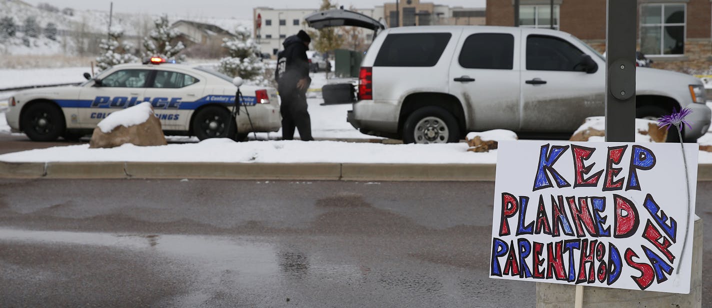 A sign in support of Planned Parenthood stands just south of the clinic as police investigators gather evidence near the scene of Friday's shooting at the clinic Sunday, Nov. 29, 2015, in northwest Colorado Springs, Colo. (AP Photo/David Zalubowski) ORG XMIT: MIN2015113016135028