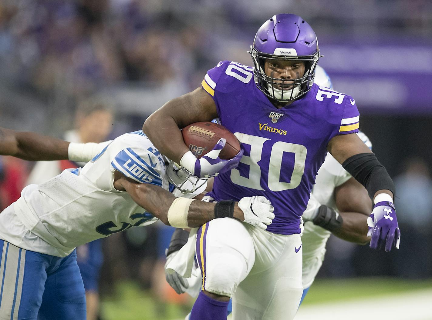 Minnesota Vikings fullback C.J. Ham ran with the ball despite defensive pressure from Detroit Lions strong safety Tavon Wilson during the second quarter.