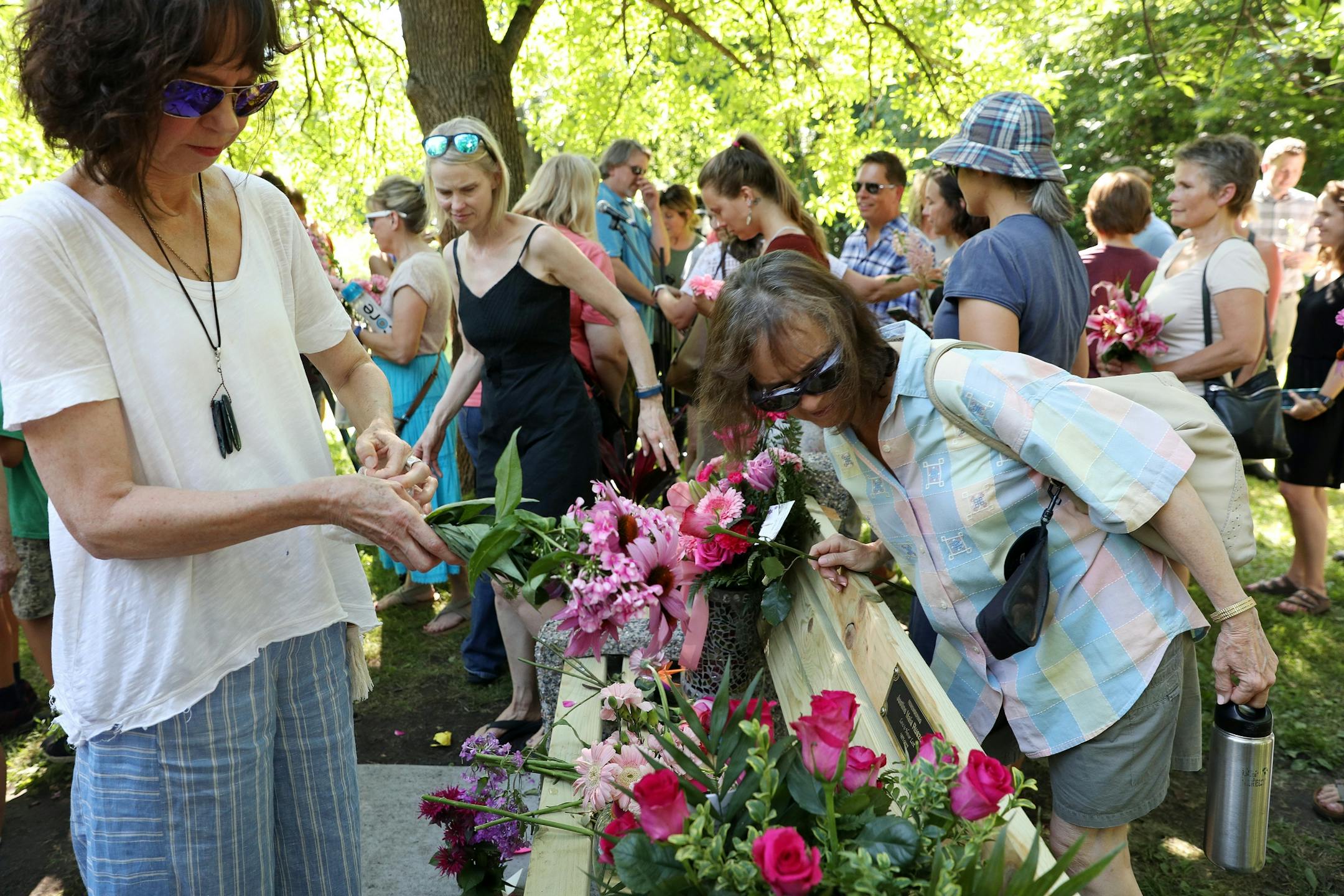 Friends and family that gathered to dedicate a bench to Justine Ruszczyk Damond at Minnehaha Creek between 53rd and 54th streets gathered up flowers to throw into the water in her honor on the one year anniversary of her death.