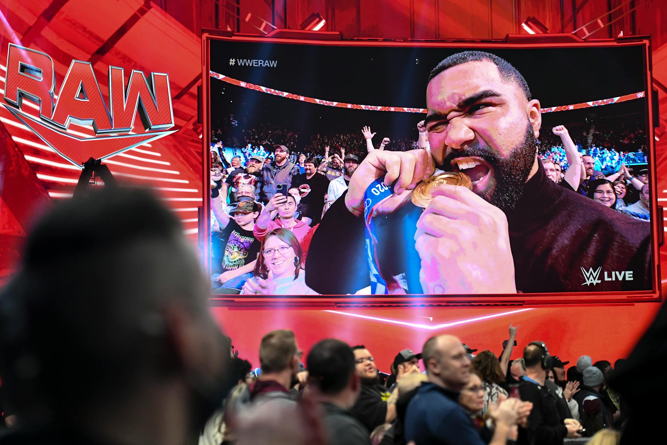 University of Minnesota wrester Gable Steveson bites his Olympic gold medal during WWE Raw Monday, Dec. 13, 2021 at the Xcel Energy Center in St. Paul, Minn.     ] AARON LAVINSKY • aaron.lavinsky@startribune.com