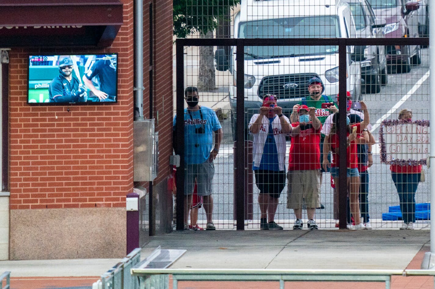 Fans peeked through the gates during a Phillies-Marlins game in Philadelphia. A COVID-19 outbreak among the Marlins has forced postponement of Monday night's games between Miami and Baltimore and between Philadelphia at the New York Yankees.