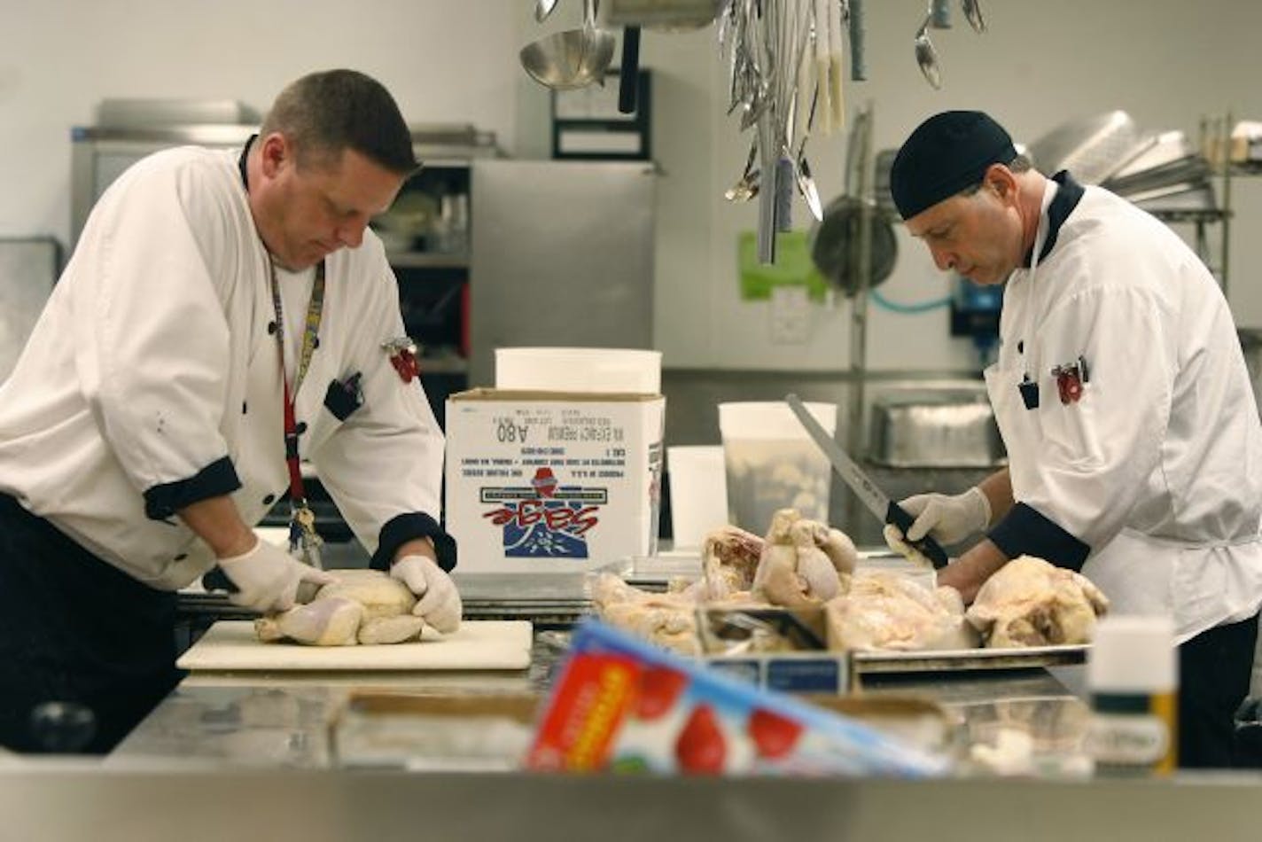 Before feeding at least 400 people, Kristoffer Landroche, left, and David Schulman prepared chicken at the House of Charity kitchen for Wednesday's menu.