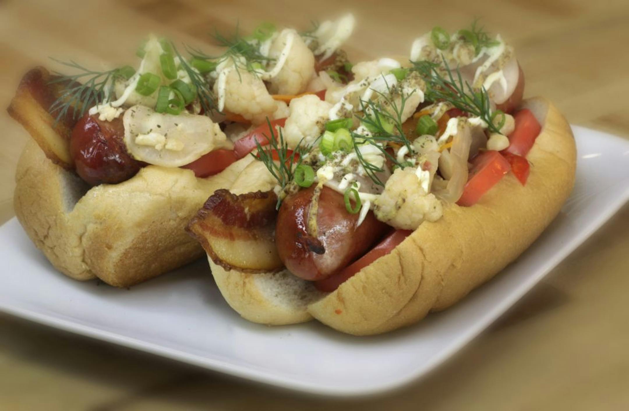 Pickled cauliflower is among the toppings for a pair of hot dogs.