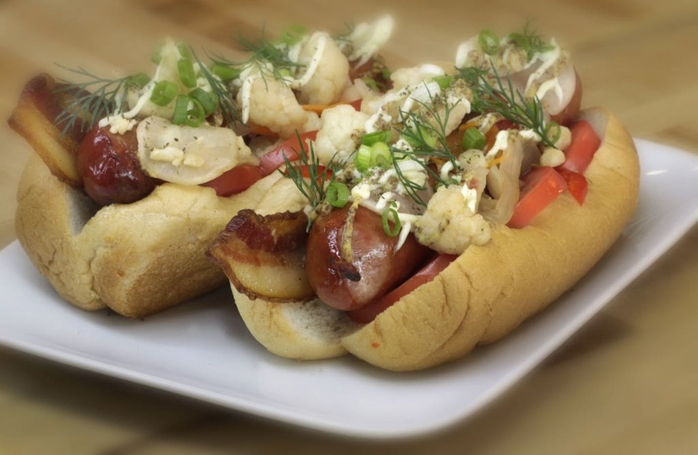 Pickled cauliflower is among the toppings for a pair of hot dogs.