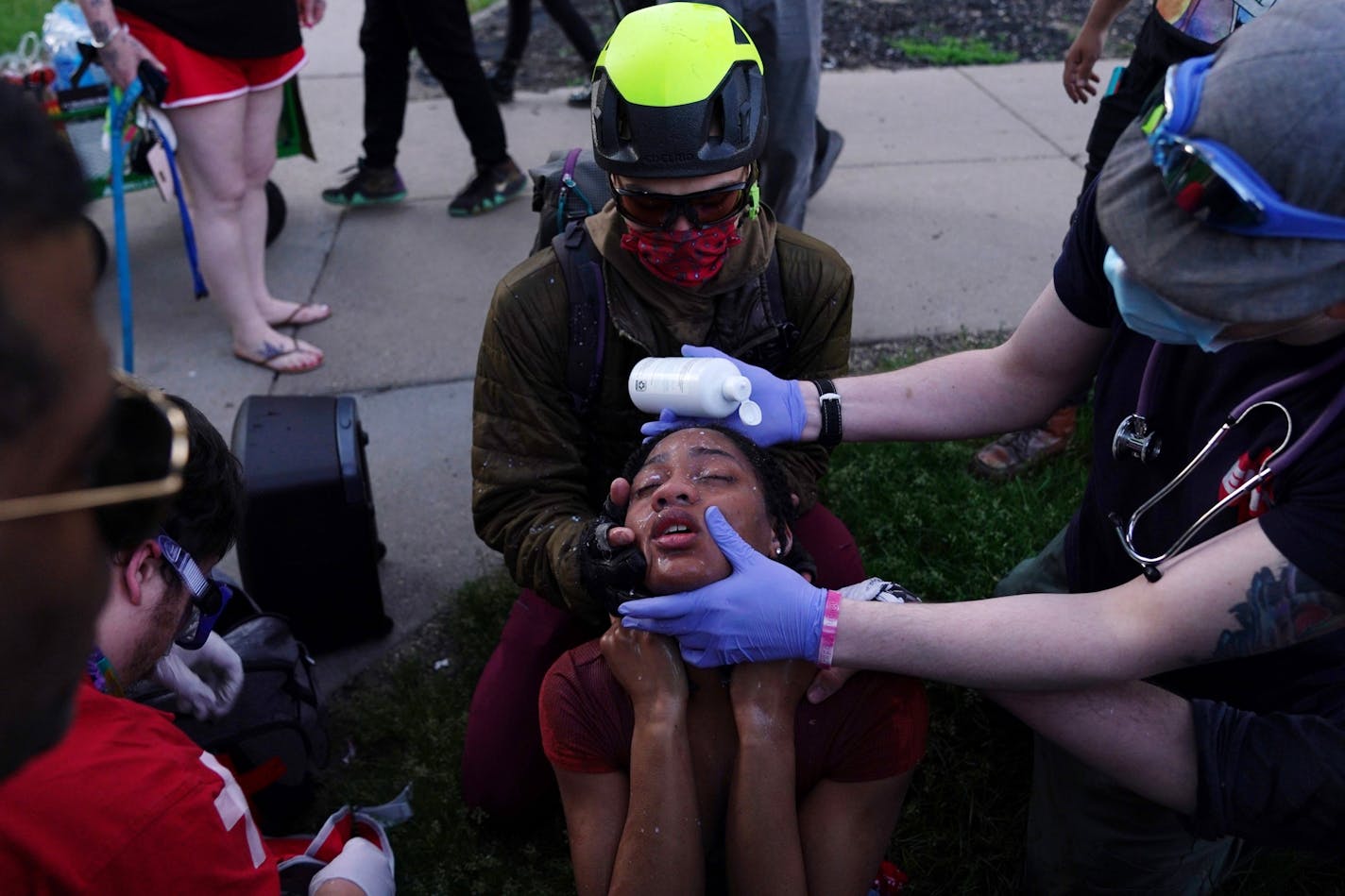 Citizen medics helped a protester clear her eyes as police moved in aggressively with tear gas to clear a group of protesters that had gathered near the Minneapolis Police 5th Precinct about a half hour after curfew Saturday.