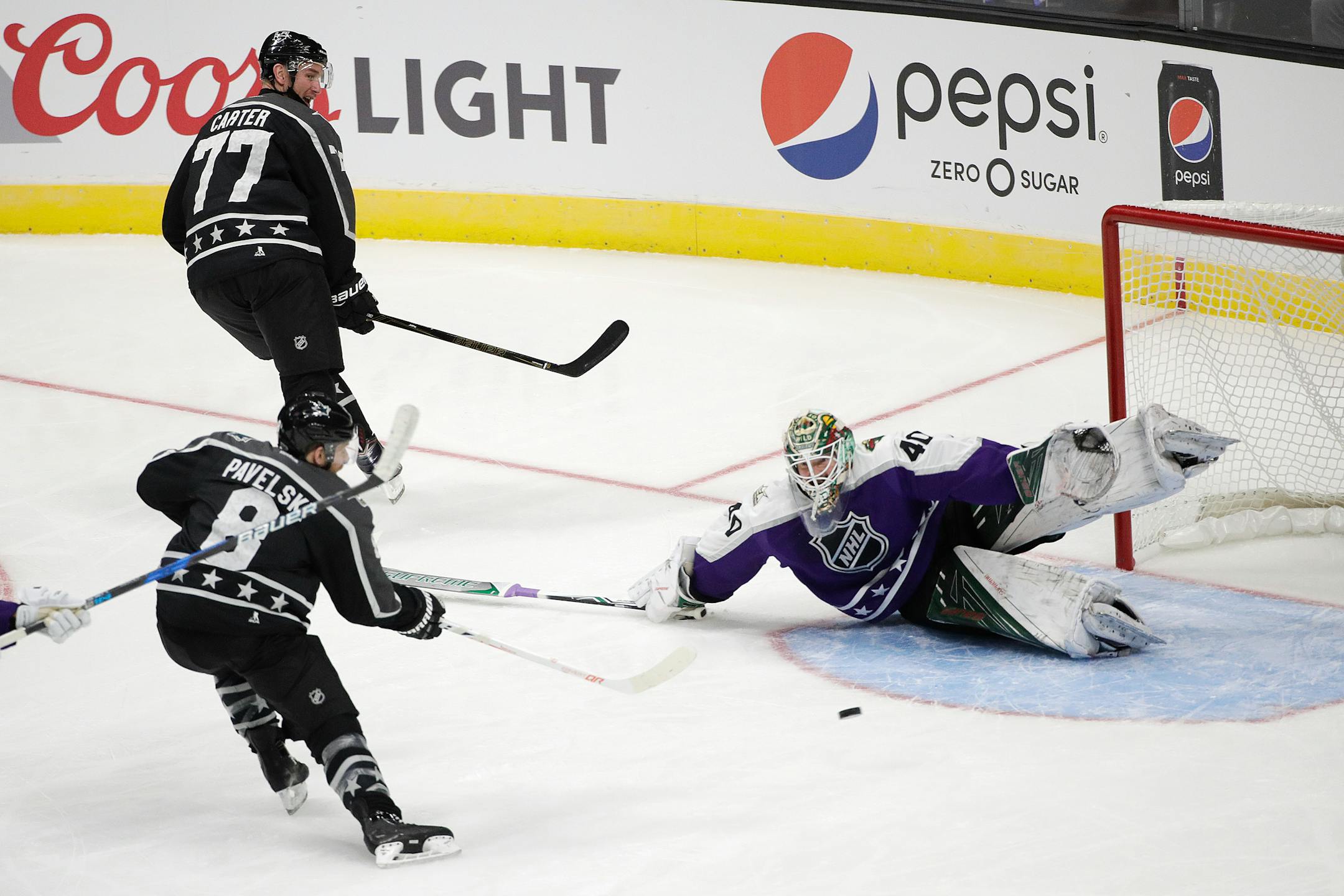 Pacific Division's Joe Pavelski (8) of the San Jose Sharks scored against Central Division goalie Devan Dubnyk of the Wild as teammate Jeff Carter (77) of the Los Angeles Kings watched during the NHL All-Star Game on Sunday in Los Angeles.