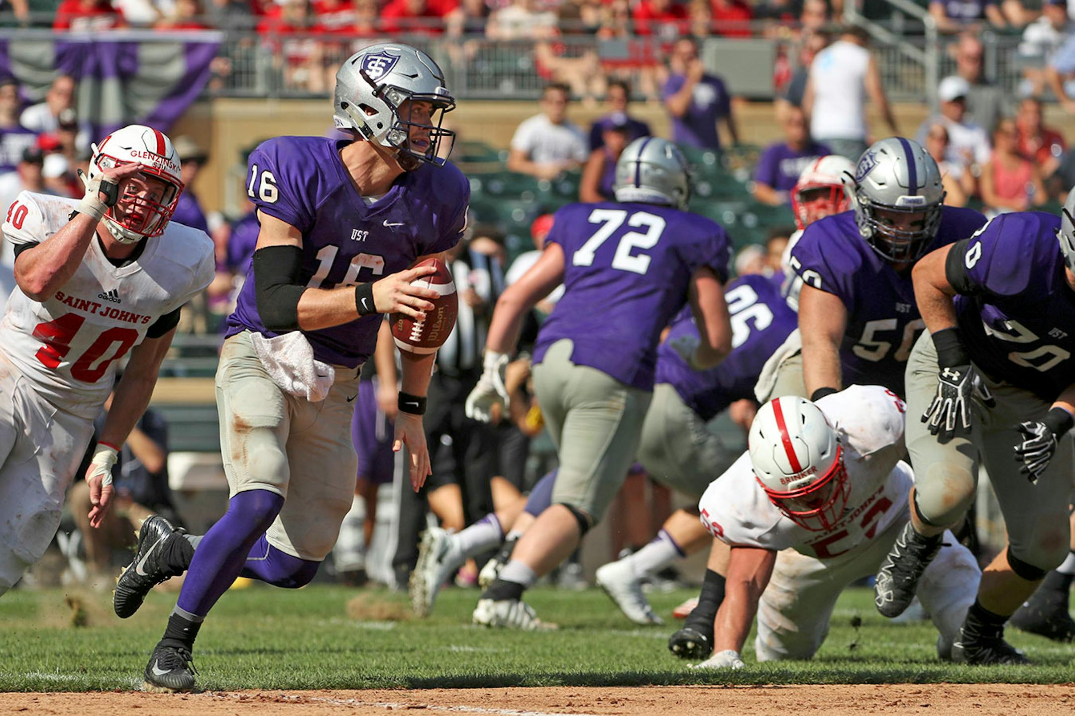 University of St. Thomas quarterback Jacques Perra (16) ran the ball as St. John's University defensive lineman Drew Glenzinski (40) chased after him in the first half.