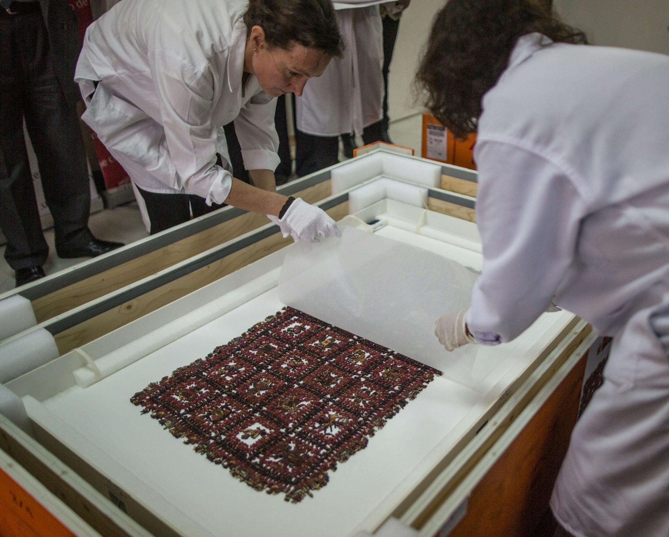 National Museum of Archaeology, Anthropology and History of Peru personnel lift a sheet of paper to reveal a Paracas textile calendar during a media presentation, at the museum in Lima. Peru, Monday, June 16, 2014. The calendar is among the first batch of ancient Paracas textiles that Sweden is returning to Peru 80 years after they were smuggled out by diplomat Sven Karell. In the early 1930s the Swedish consul had secreted them out of Peru after they were discovered in the Paracas Peninsula, a