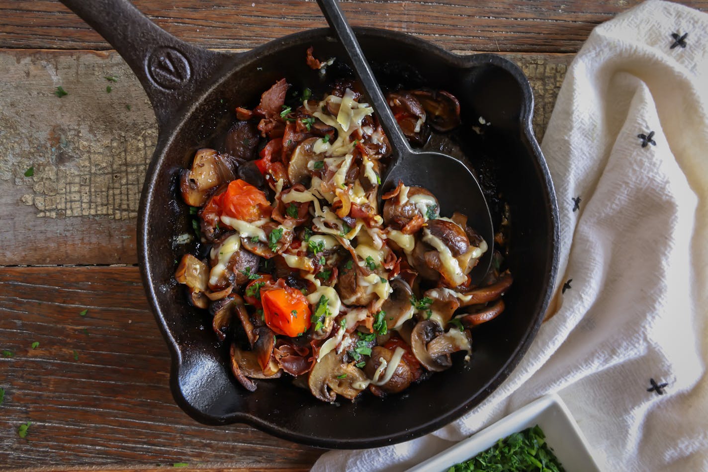 A variety of mushrooms are sauteed into a stew with cherry tomatoes and onions.