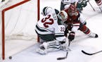 Arizona Coyotes center Brad Richardson, right, sends the puck just wide of Minnesota Wild goaltender Alex Stalock (32) during the second period of an 