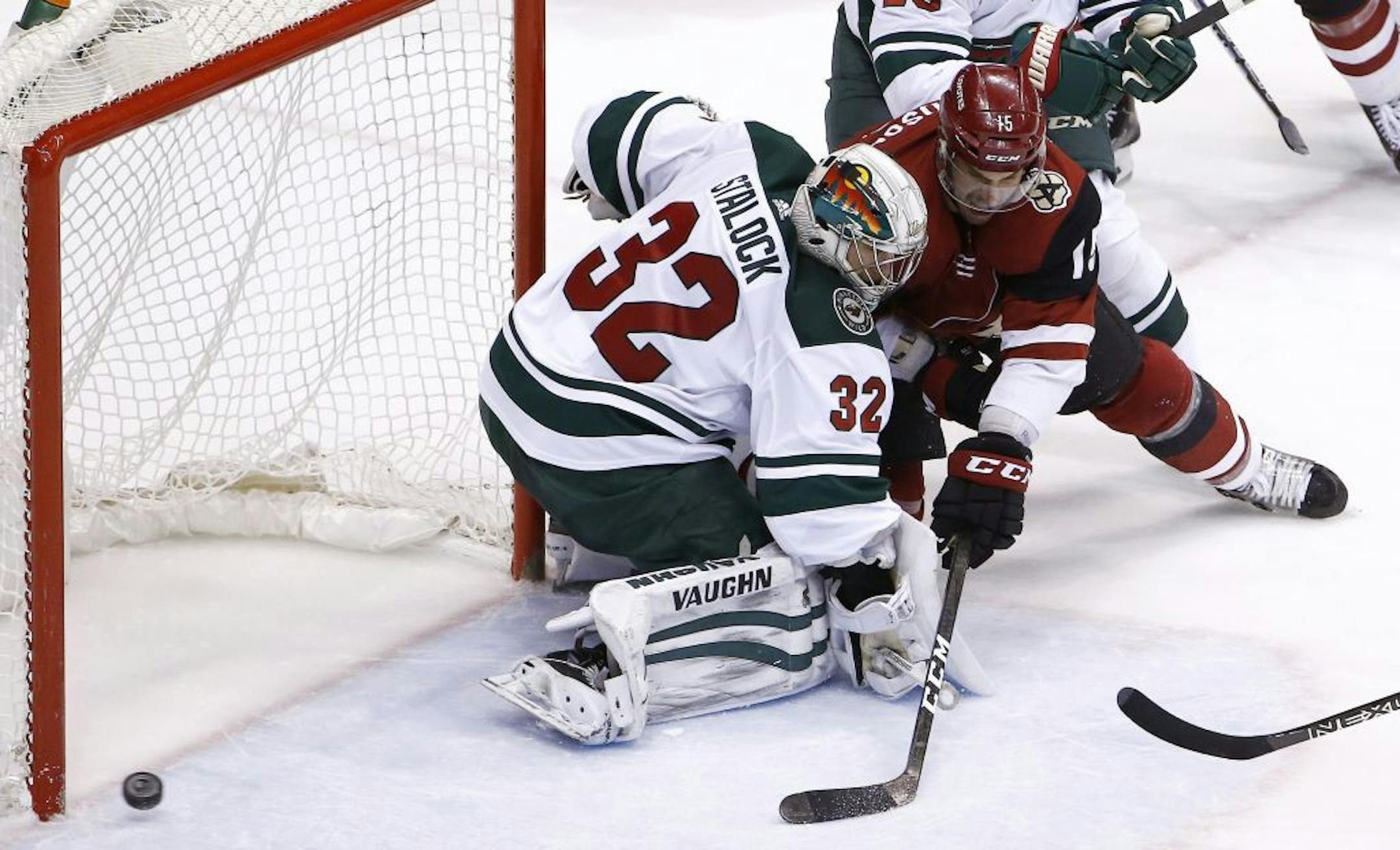 Arizona Coyotes center Brad Richardson, right, sends the puck just wide of Minnesota Wild goaltender Alex Stalock (32) during the second period of an NHL hockey game Thursday, March 1, 2018, in Glendale, Ariz.