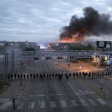 FILE - In this Friday, May 29, 2020 file photo, law enforcement officers stand in formation along Lake Street near Hiawatha Avenue as fires burned after a night of unrest and protests in the death of George Floyd in Minneapolis. Floyd died after being restrained by Minneapolis police officers on Memorial Day. (David Joles/Star Tribune via AP)