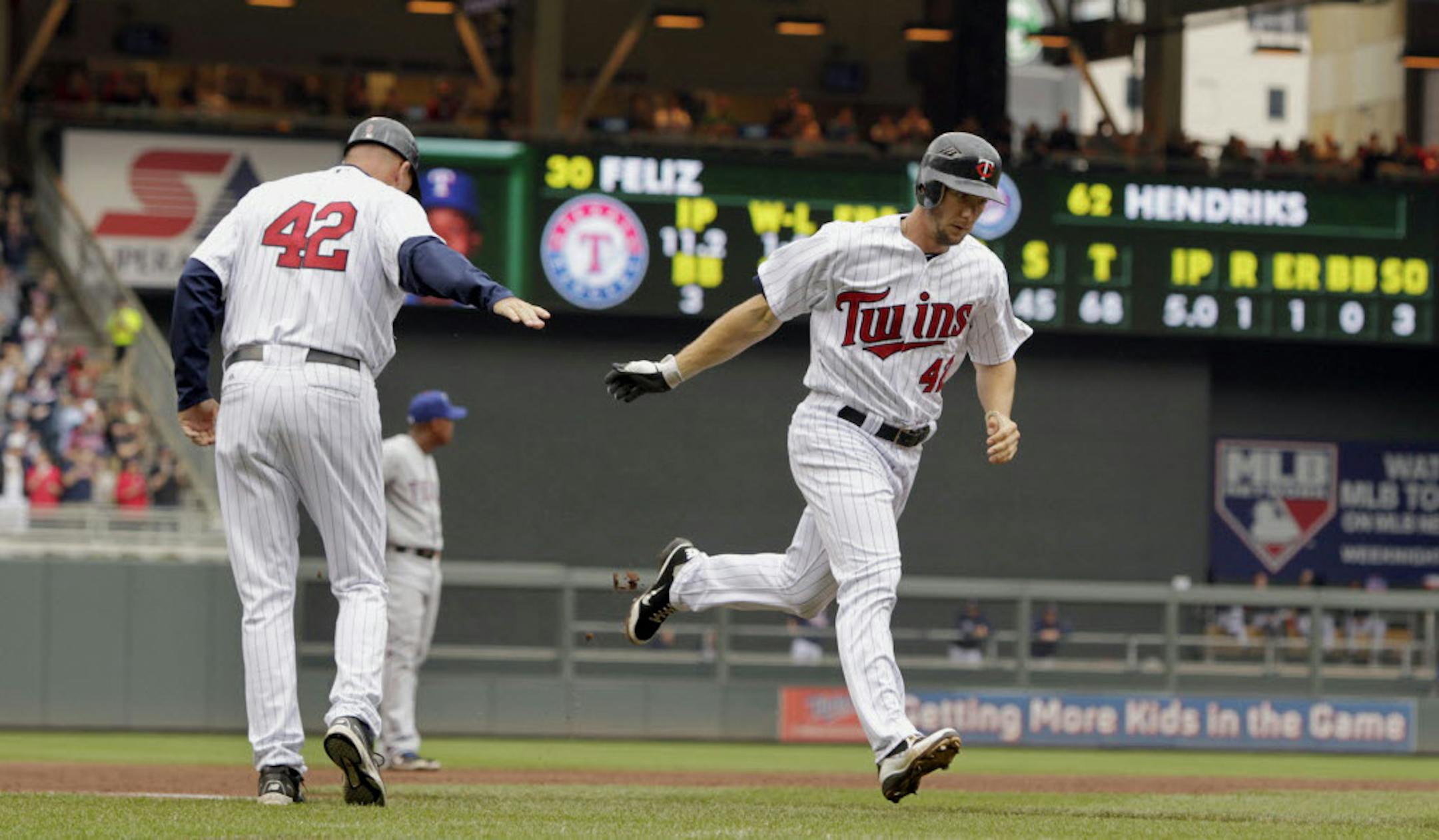 Minnesota's Clete Thomas is congratulated by third base coach Steve Liddle as he runs toward home plate after a two-run home run in the fifth inning.