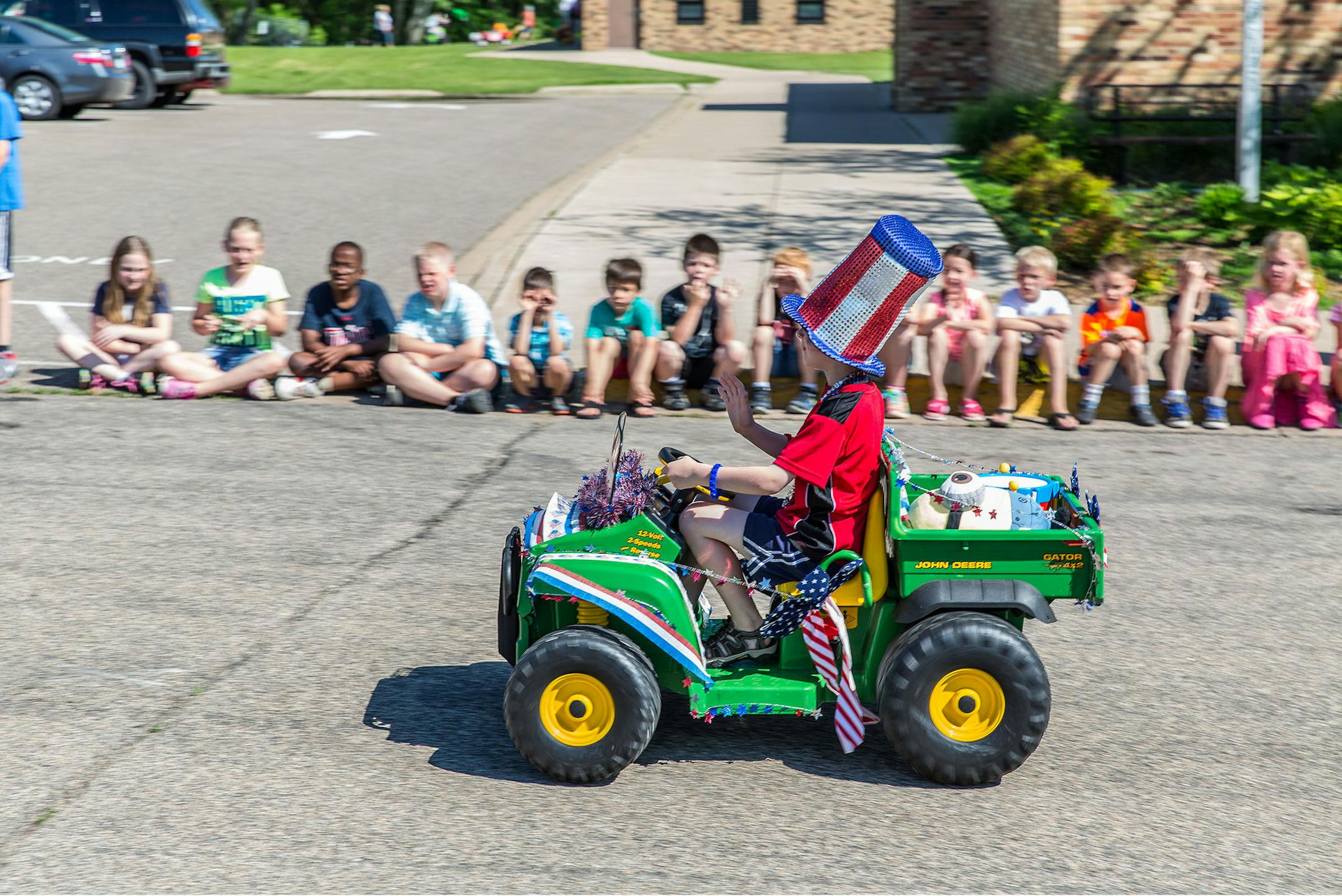 Luke Peterson waves as he rides a miniature John Deere Gator during a parade at Centerville Elementary School. Photo by Bob Mallory