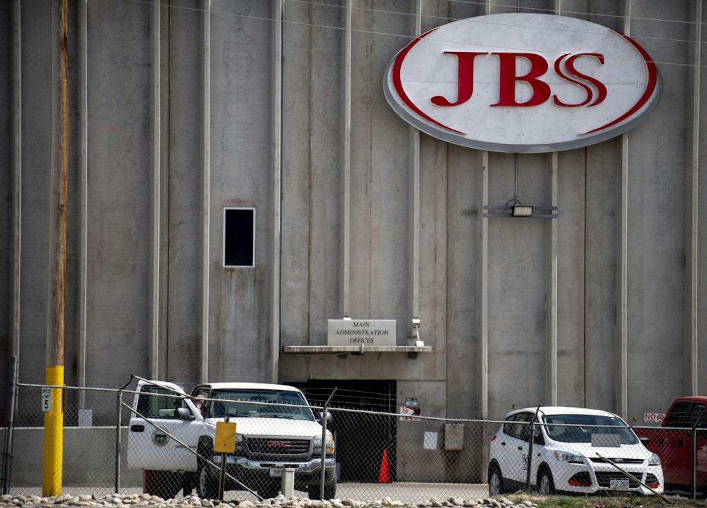 FILE - In this April 8, 2020, file photo, a truck bearing Weld County insignia sits outside the administrative office entrance at JBS USA in Greeley, Colo. A major meatpacking plant in Colorado that was closed because of the coronavirus is set to reopen Friday, April 24, 2020, after disinfecting the facility over the last two weeks, even as some question how workers will be able to maintain social distancing to curb the spread of the disease. The plant in Greeley was closed April 11 after health