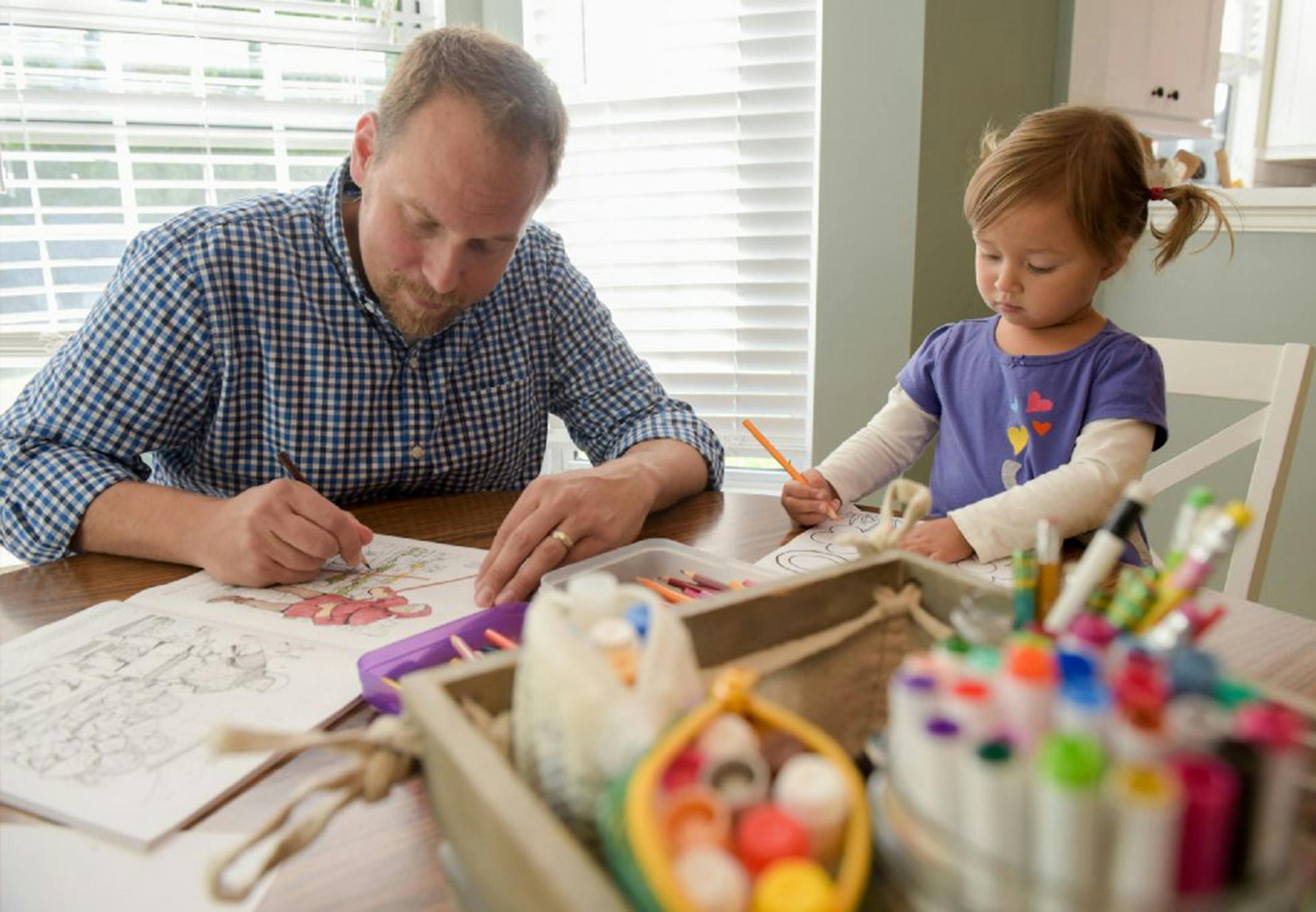 Michael Johnson of Carol Stream, Ill. and his daughter Isabelle, 2 color some drawings on Thursday, Oct. 4, 2018. The Johnsons found that getting health insurance through Samaritan Ministries was cheaper than a traditional policy. (Mark Black/Chicago Tribune/TNS) ORG XMIT: 1242693