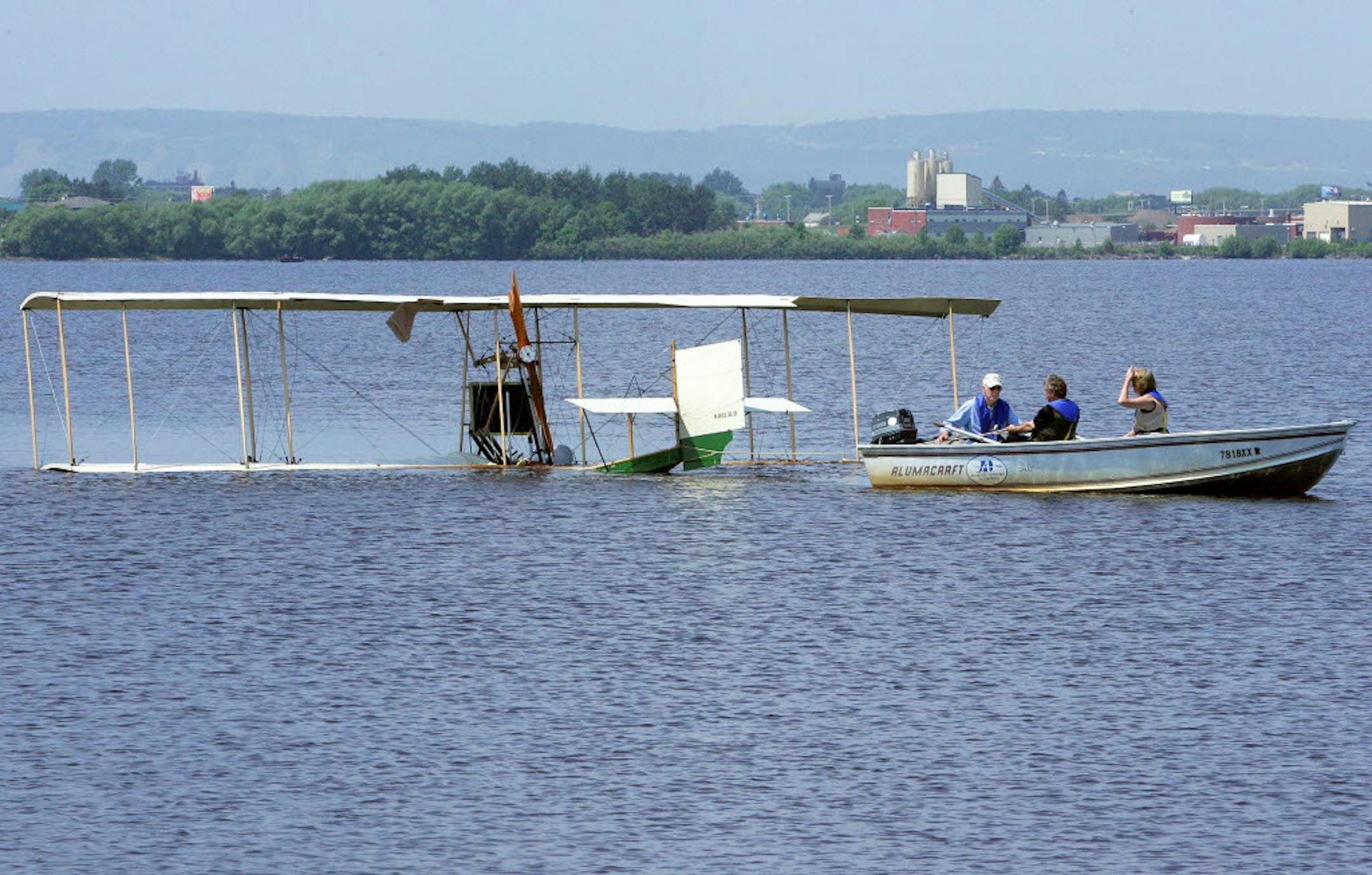 A Duluth Airport Authority boat tows the Lark of Duluth replica float biplane to shore Tuesday after it crash-landed in Superior Bay.