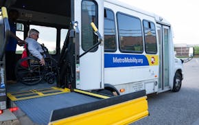 Mark Hughes boards a Metro Mobility van outside the library in Woodbury on Friday. The Metro Mobility van was scheduled to arrive at the pickup loc