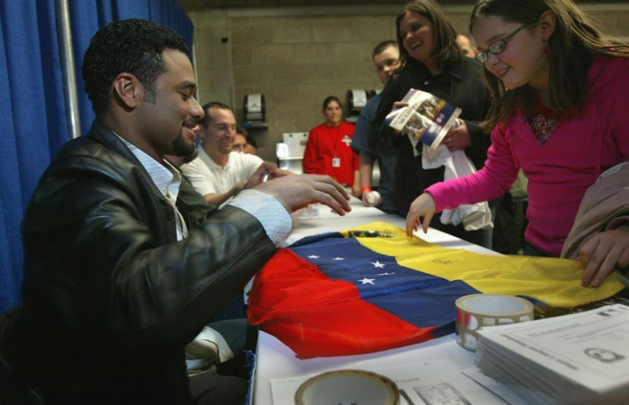 staff photo tom sweeney Minneapolis, MN 1/28/2005 Twins' pitcher Johan Santana appeared pleased to be presented with the flag of his native Venezuala to autograph, by Jane Lindemannn ( right) of St. Louis Park,- she received it as a Christmas gift in anticipation of this occaision