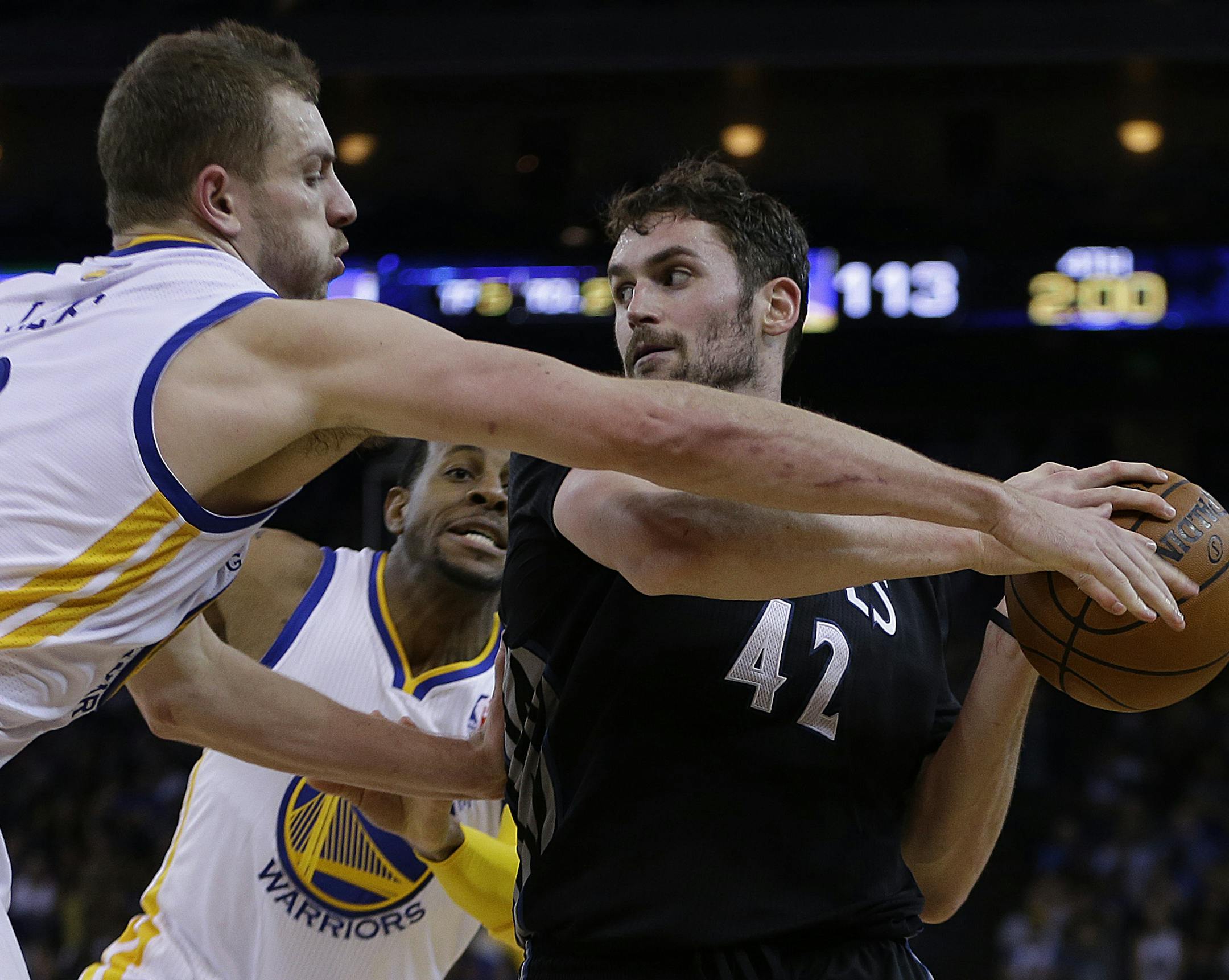 Minnesota Timberwolves' Kevin Love (42) keeps the ball from Golden State Warriors' David Lee, left, and Andre Iguodala, center, during the second half of an NBA basketball game Friday, Jan. 24, 2014, in Oakland, Calif. (AP Photo/Ben Margot)