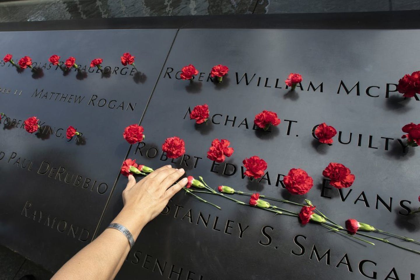 Norma Molina, of San Antonio, Texas, leaves flowers by the names of firefighters from Engine 33 at the September 11 Memorial, Monday, Sept. 9, 2019, in New York. Her boyfriend Robert Edward Evans, a member of Engine 33, was killed in the north tower of the World Trade Center on Sept. 11, 2001.