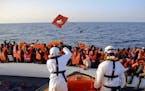 Safety jackets are thrown to migrants on a rubber dinghy rescued by the vessel Responder, run by the Malta-based NGO Migrant Offshore Aid Station (MOA