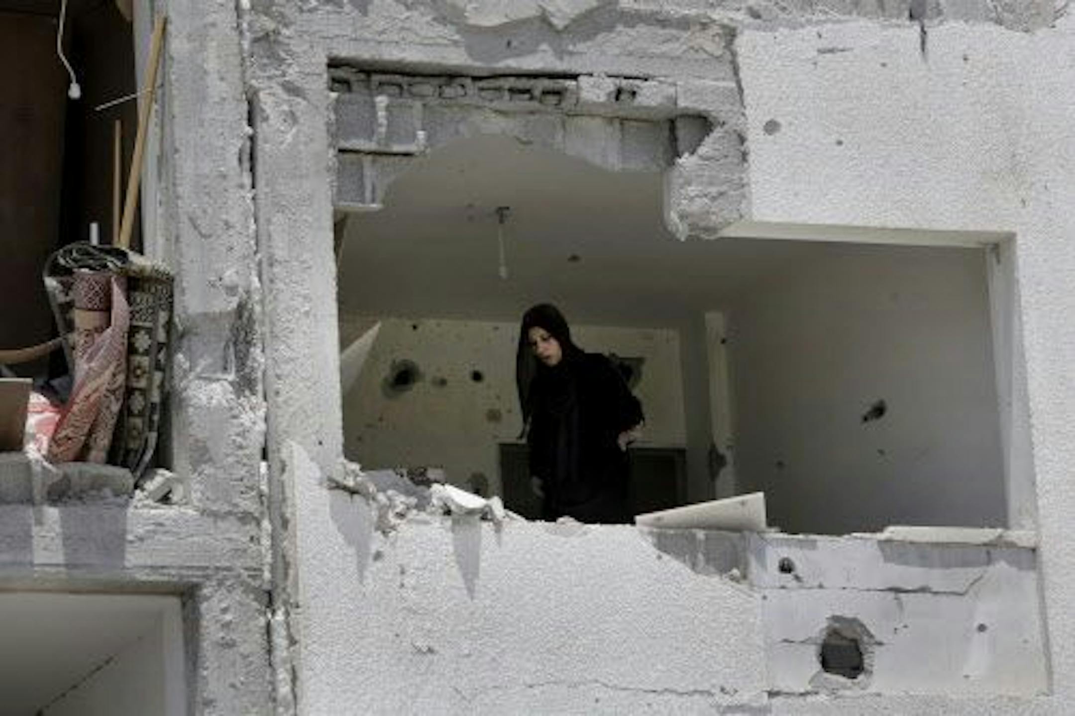 A Palestinian woman salvages what she can of her belongings from the rubble of her destroyed apartment in a building hit by an Israeli strike in Beit Lahiya, the northern Gaza Strip, Monday, Aug. 4, 2014.