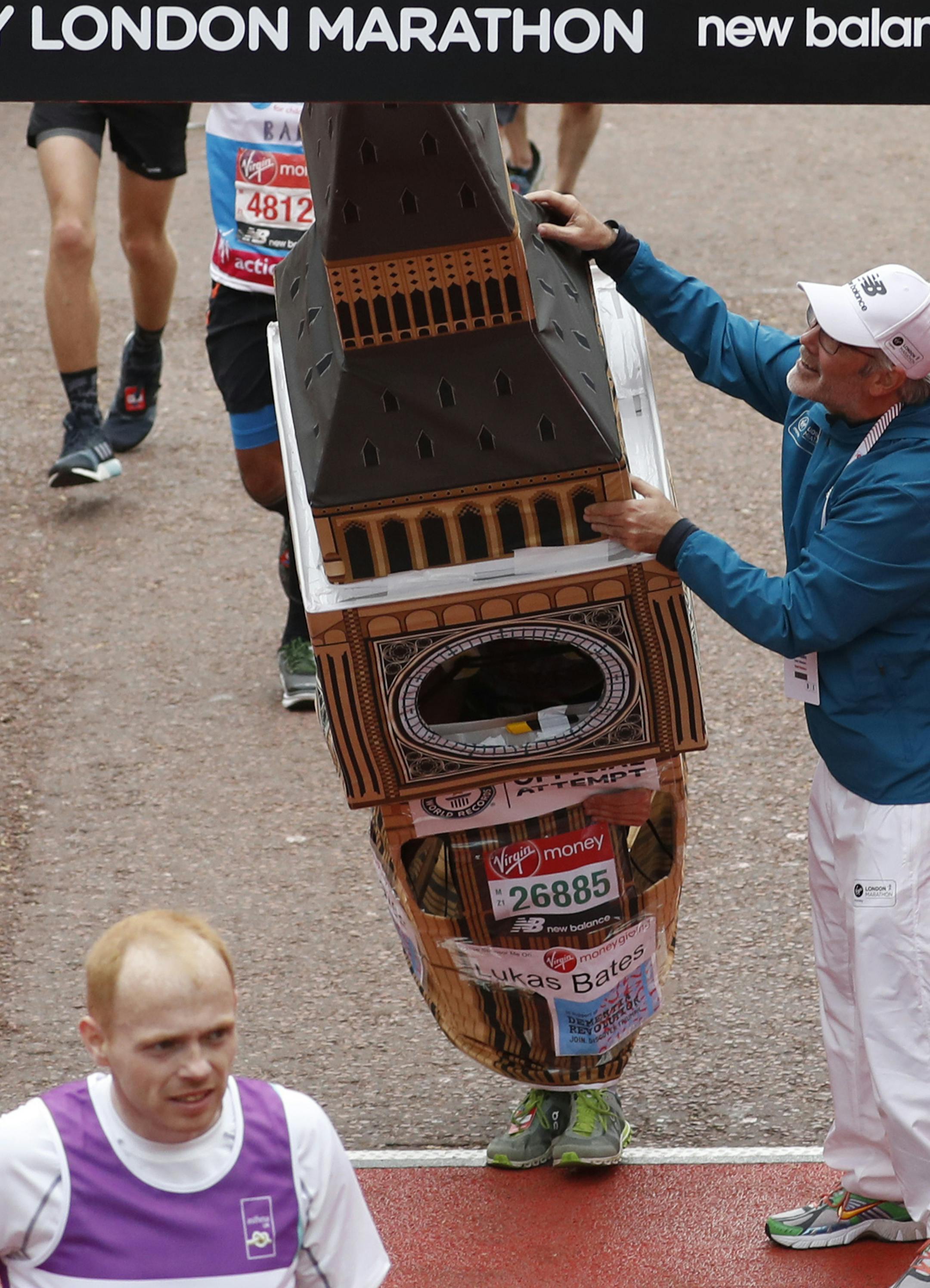 Lukas Bates wearing a costume of the Queen Elizabeth Tower (known as Big Ben) is helped by an official as he attempts to get past the finishing line, during the 39th London Marathon in London, Sunday, April 28, 2019. (AP Photo/Alastair Grant)
